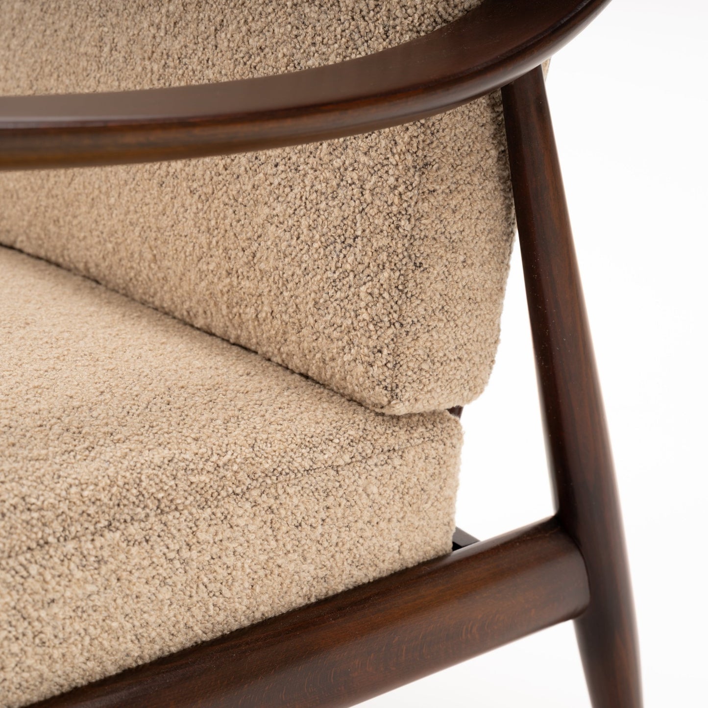Peter Hvidt Model FD 145 Lounge Chair close detail of dark wood frame curved rail tapered leg and beige textured upholstery in vintage Danish furniture style