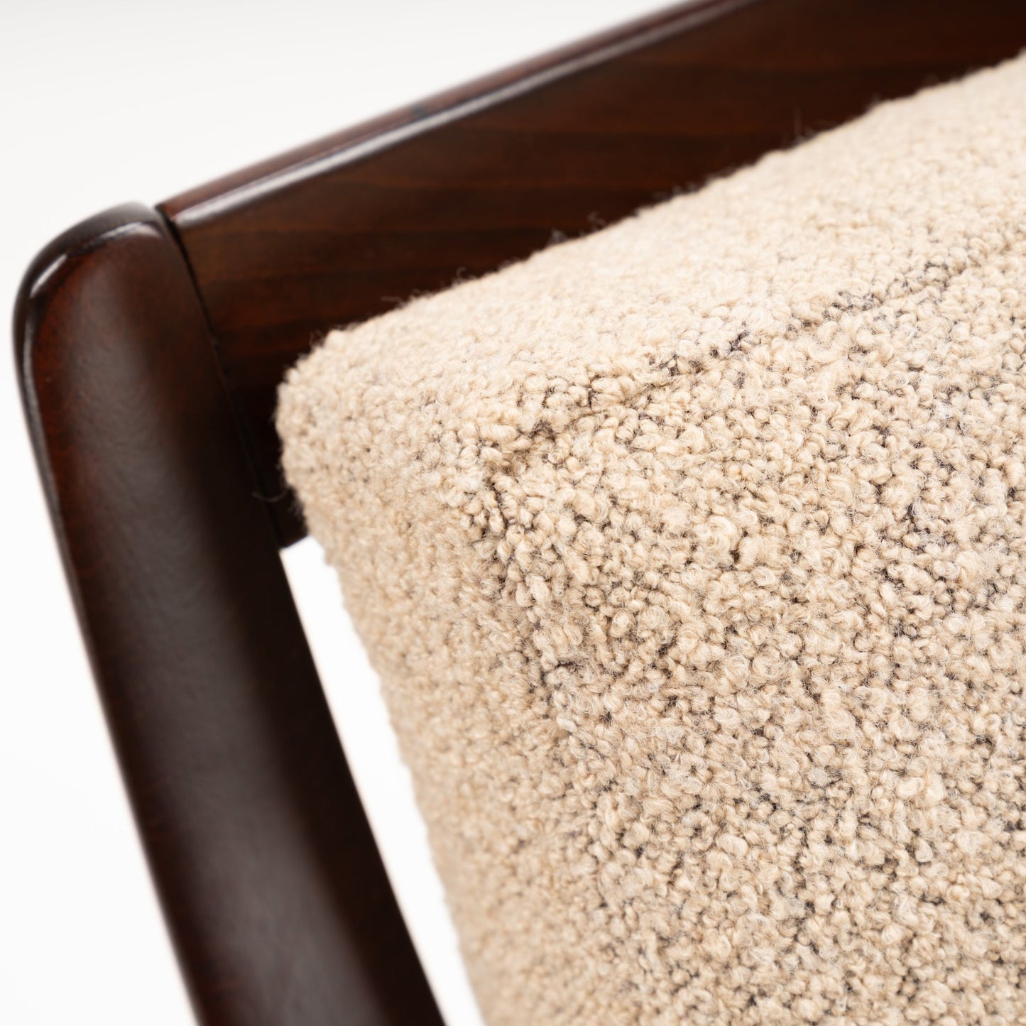 Peter Hvidt Model FD 145 Lounge Chair close detail of dark sculpted wood arm and textured beige boucle upholstery in vintage Danish furniture style