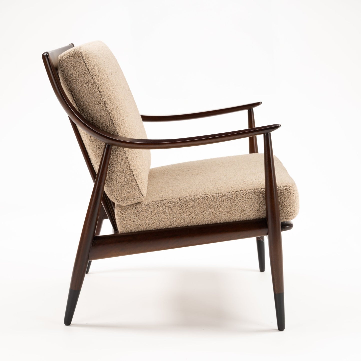 Peter Hvidt Model FD 145 Lounge Chair in side view with dark sculpted wood frame curved arms beige textured upholstery and tapered legs in vintage Danish furniture style