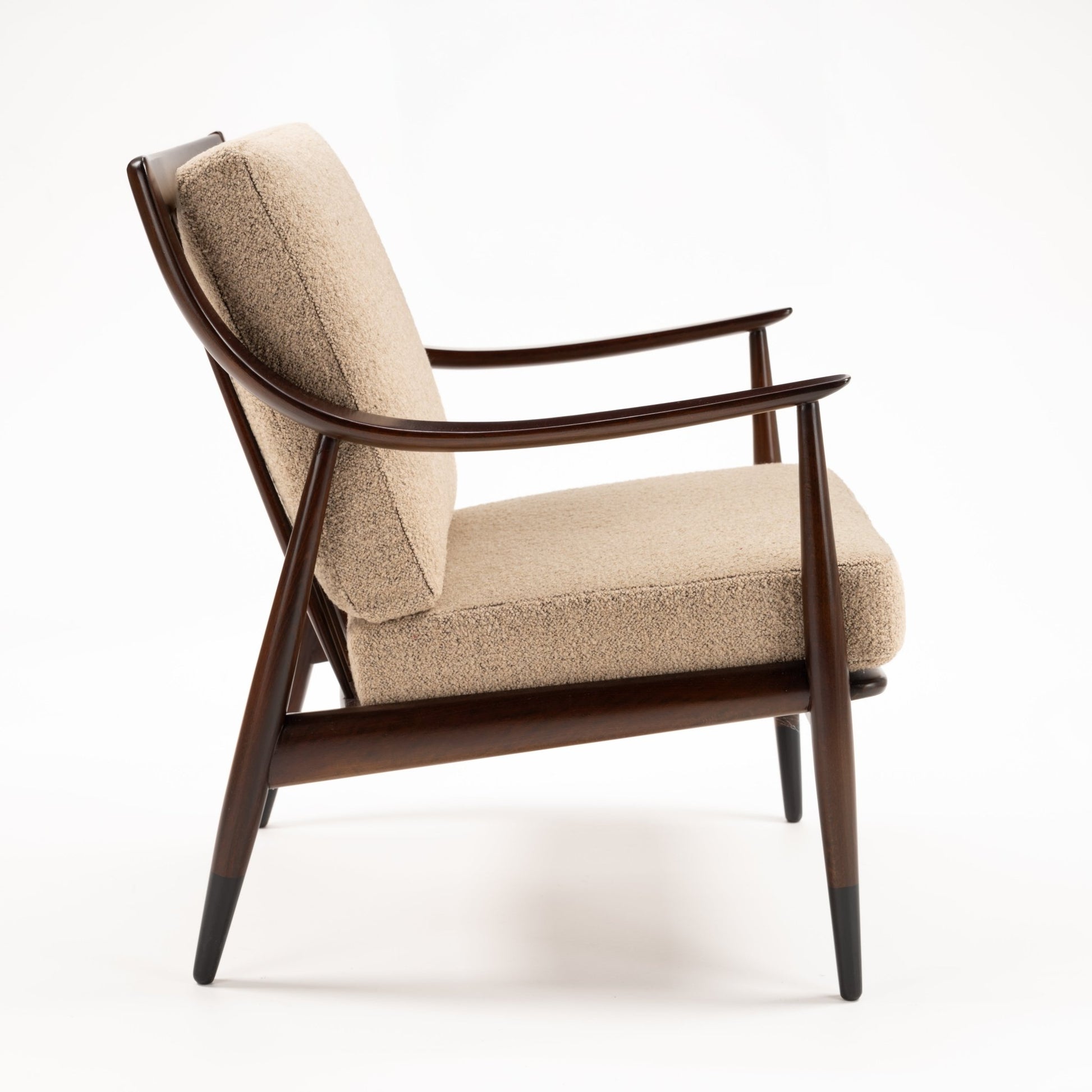 Peter Hvidt Model FD 145 Lounge Chair in side view with dark sculpted wood frame curved arms beige textured upholstery and tapered legs in vintage Danish furniture style