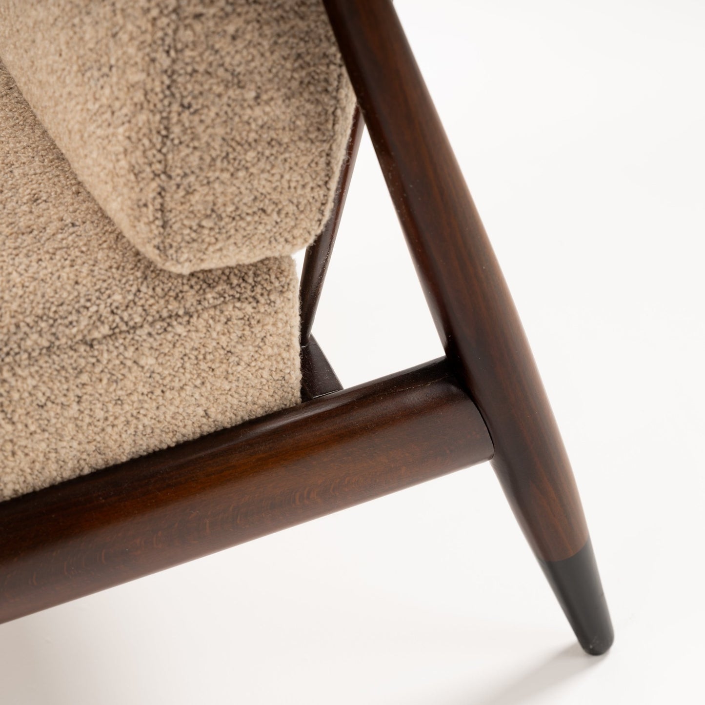 Peter Hvidt Model FD 145 Lounge Chair close detail showing dark sculpted wood frame tapered leg and textured beige upholstery in vintage Danish furniture style