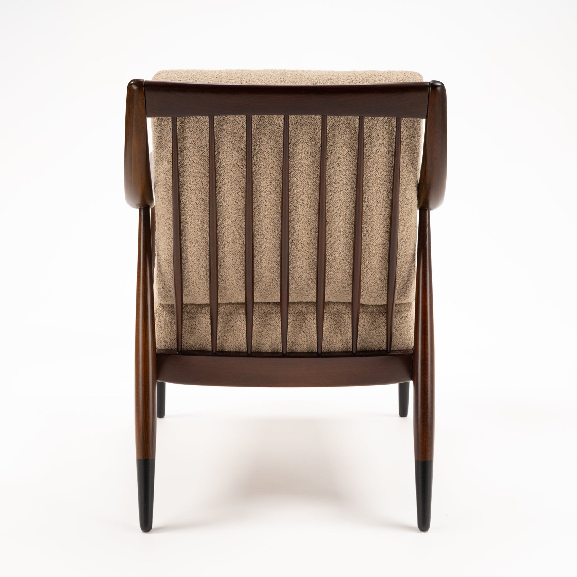 Peter Hvidt Model FD 145 Lounge Chair viewed from the rear with dark wood frame vertical spindles beige upholstered back and tapered legs in vintage Danish furniture style