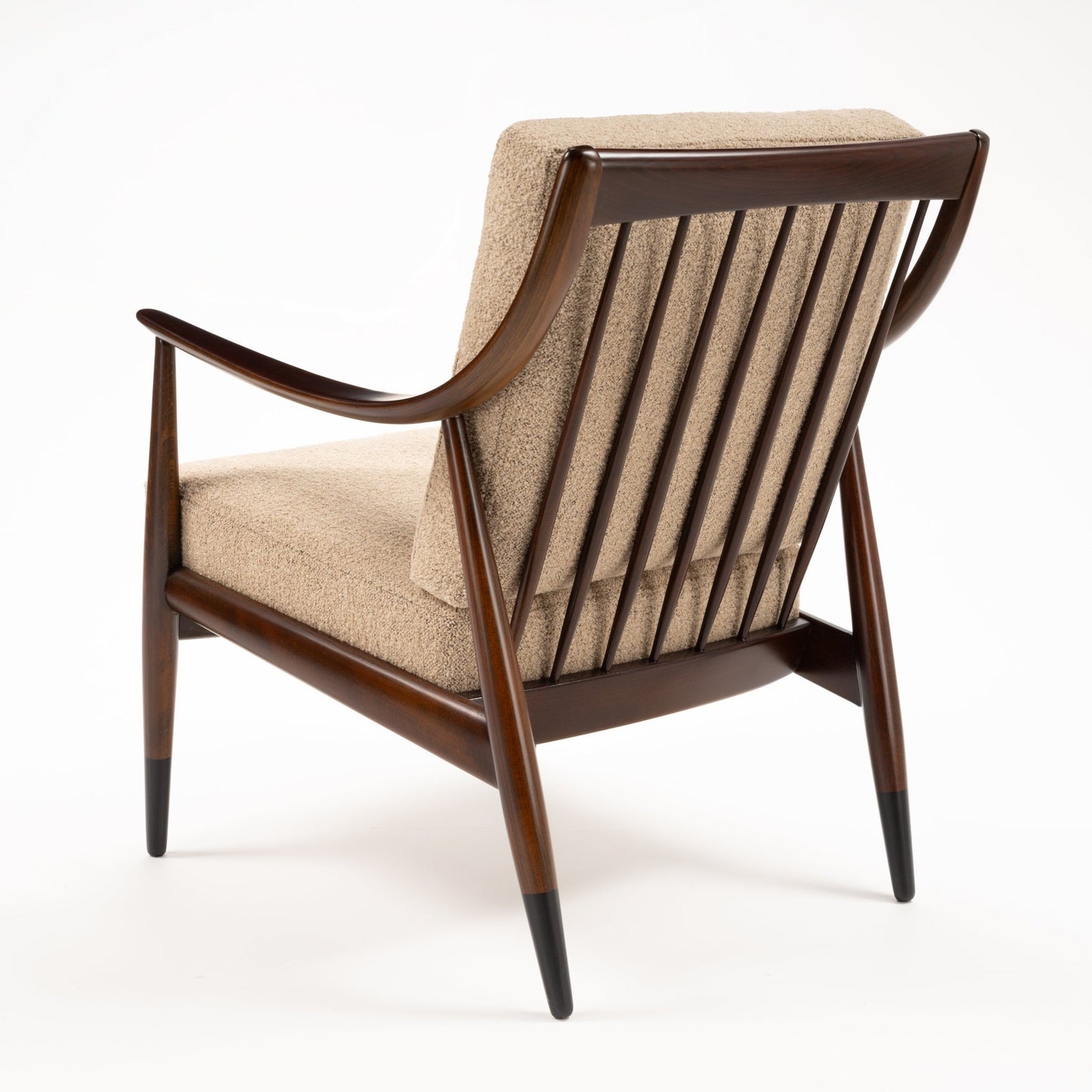 Peter Hvidt Model FD 145 Lounge Chair viewed from behind with dark sculpted wood frame spindle back beige upholstery and tapered legs in vintage Danish furniture style