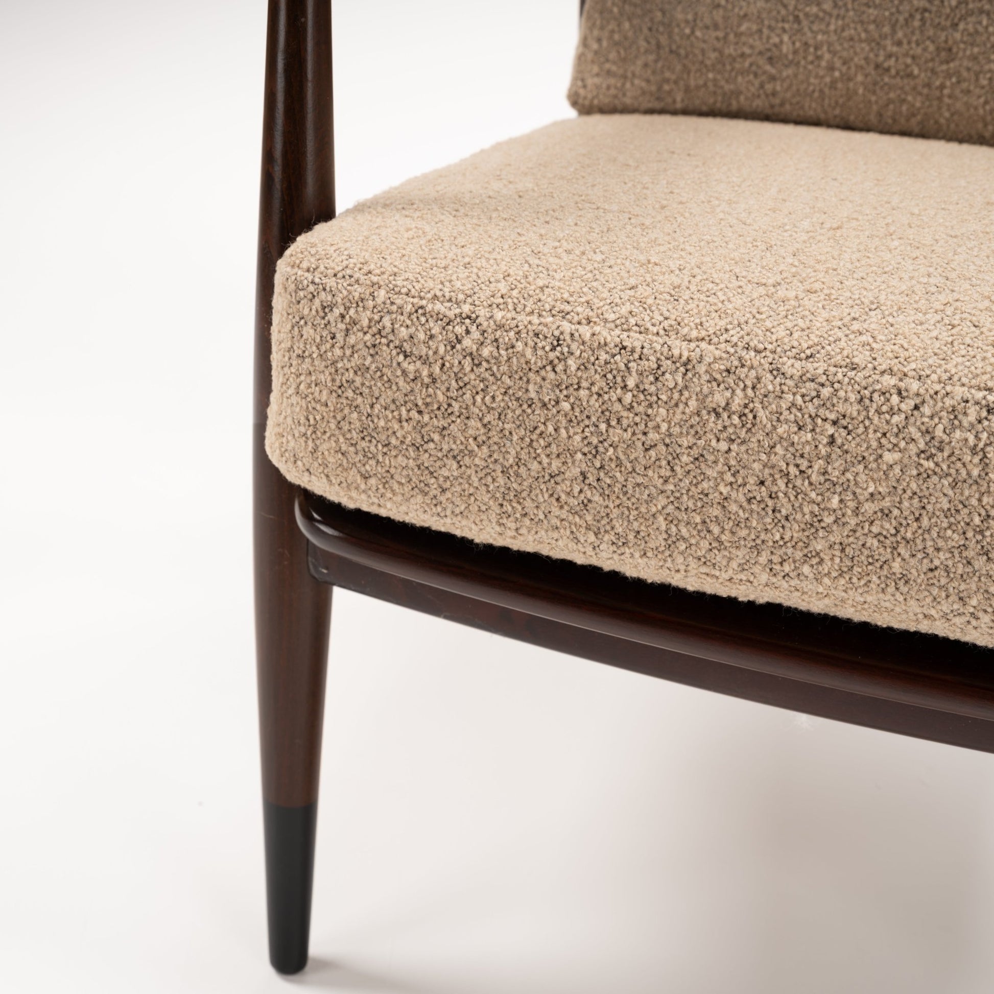 Peter Hvidt Model FD 145 Lounge Chair close view of beige boucle seat cushion dark wood frame and tapered leg in vintage Danish furniture style