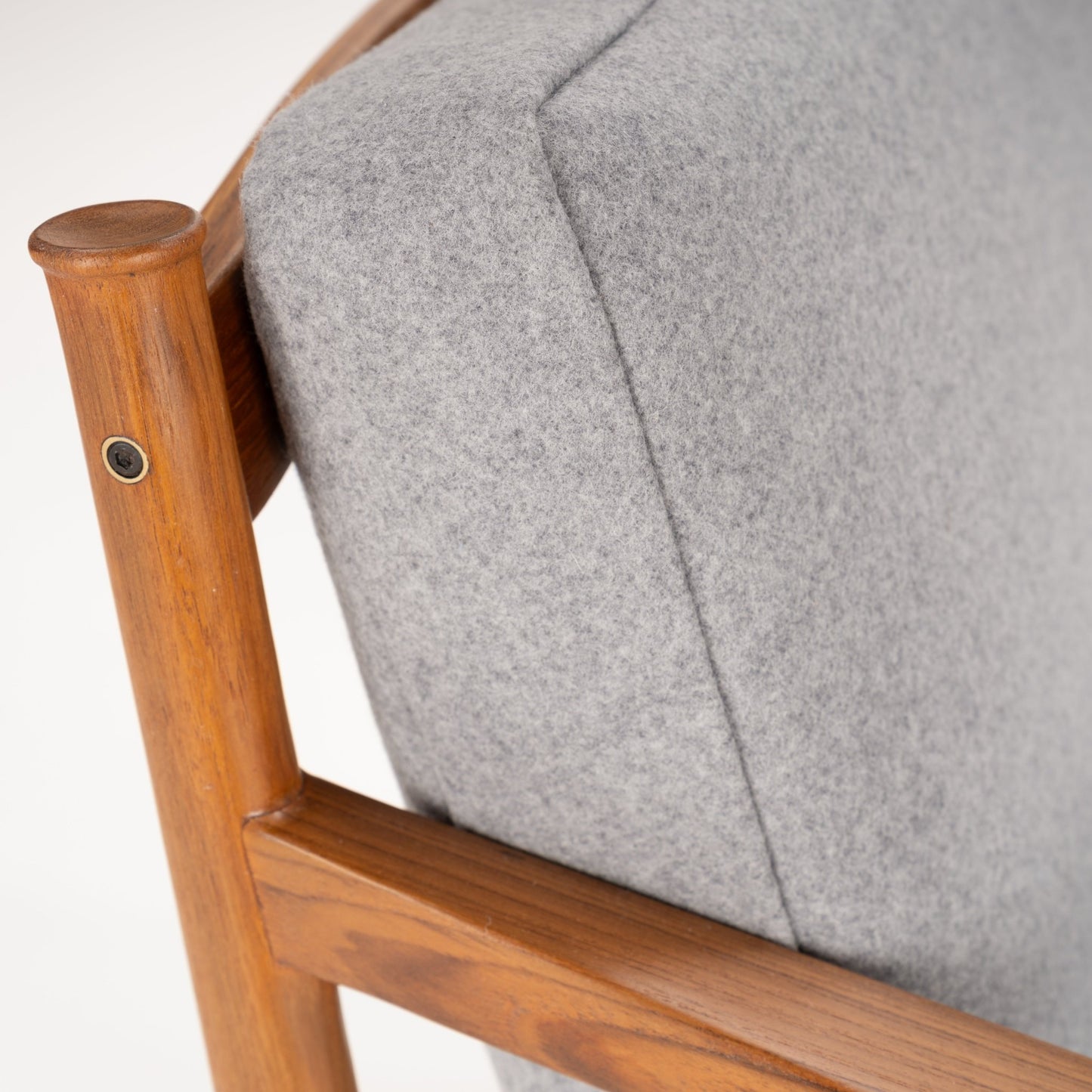 Close-up of light grey fabric cushion and warm wooden frame showing smooth armrest and joint detail on chair