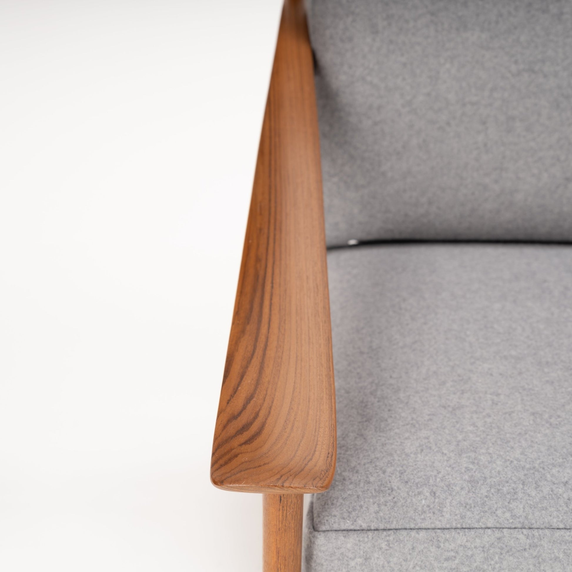 Close-up of a polished wooden armrest with visible grain paired with a light grey fabric seat cushion on a chair
