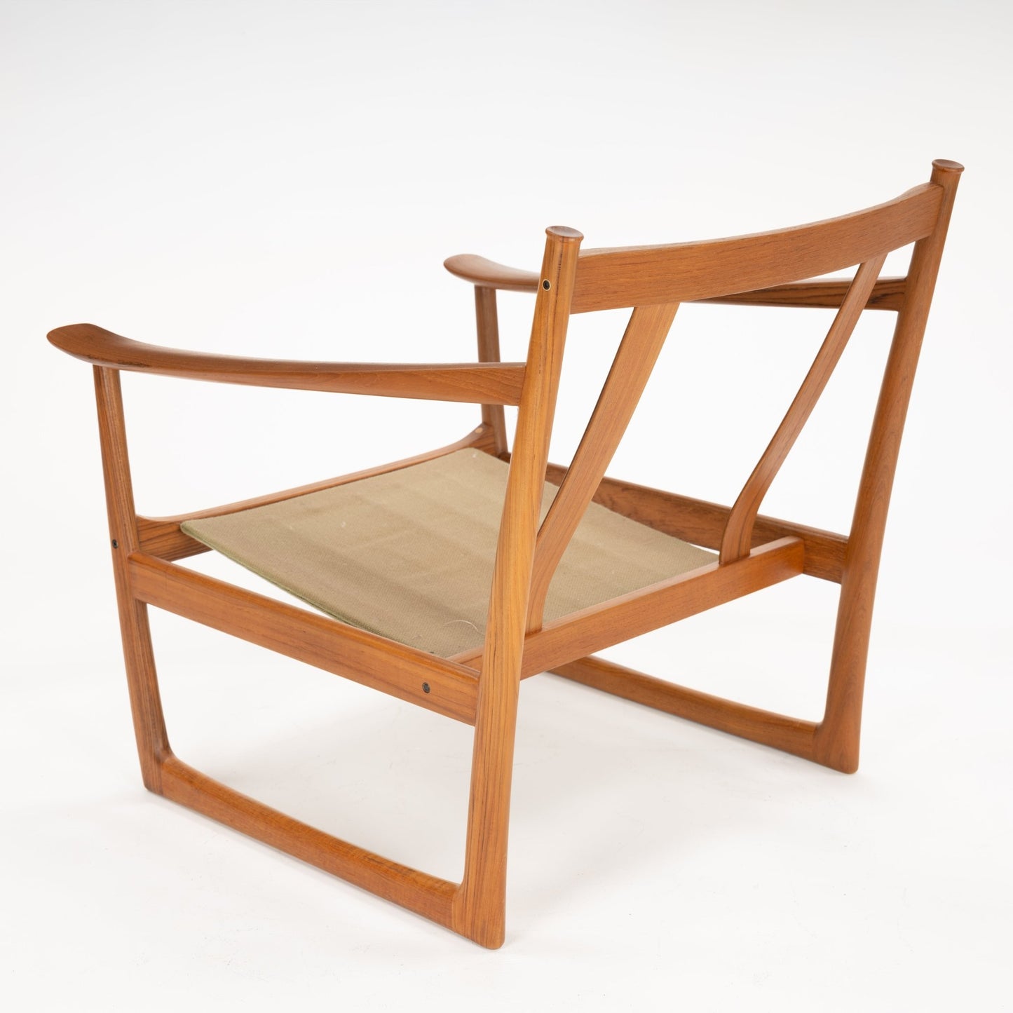 Three-quarter rear view of a wooden chair frame with wide armrests and beige fabric sling seat on white background