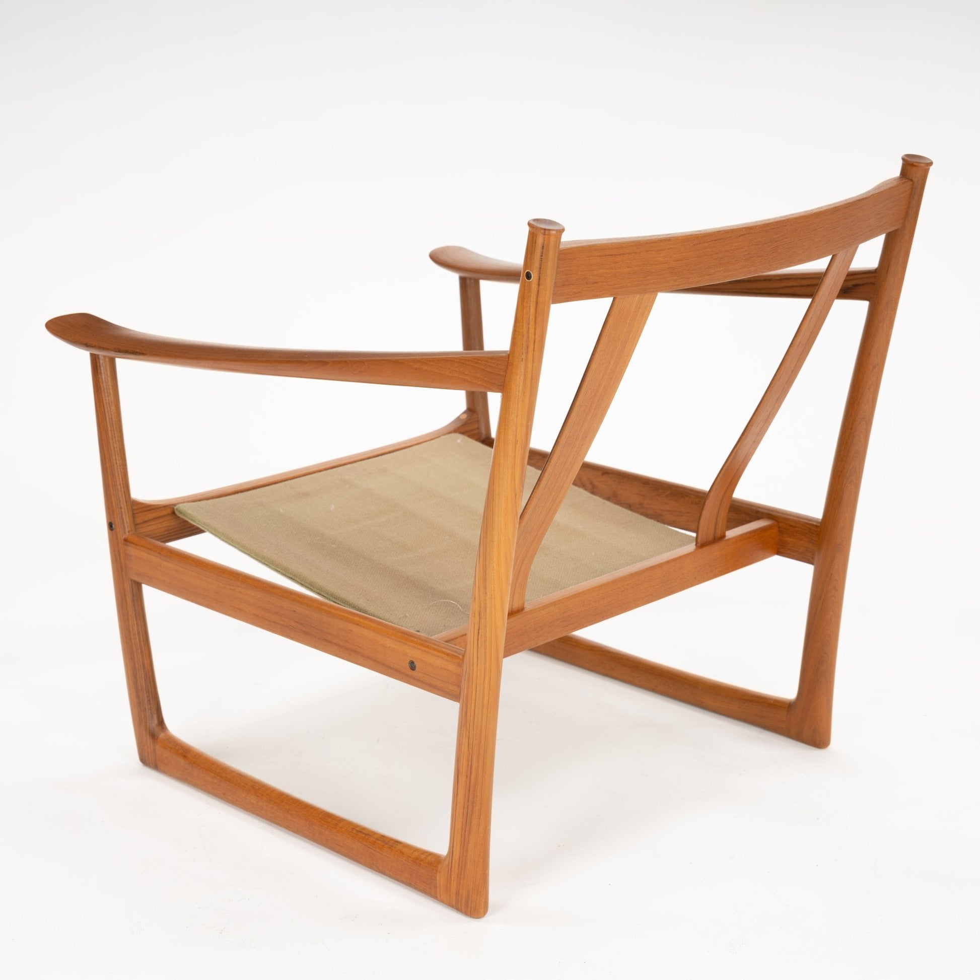 Three-quarter rear view of a wooden chair frame with wide armrests and beige fabric sling seat on white background