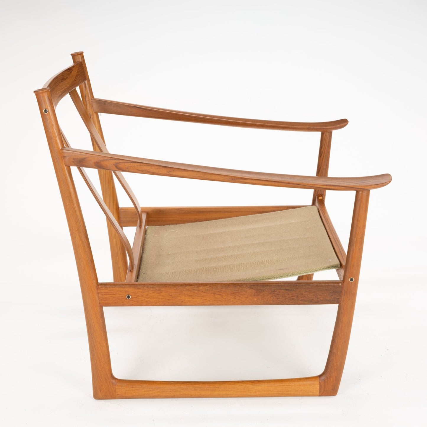 Side profile of a wooden chair frame with angled armrests and a beige fabric seat sling on white background