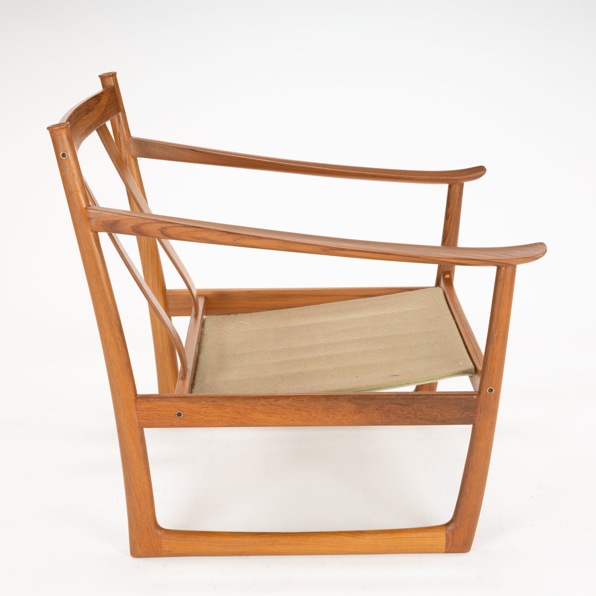 Side profile of a wooden chair frame with angled armrests and a beige fabric seat sling on white background
