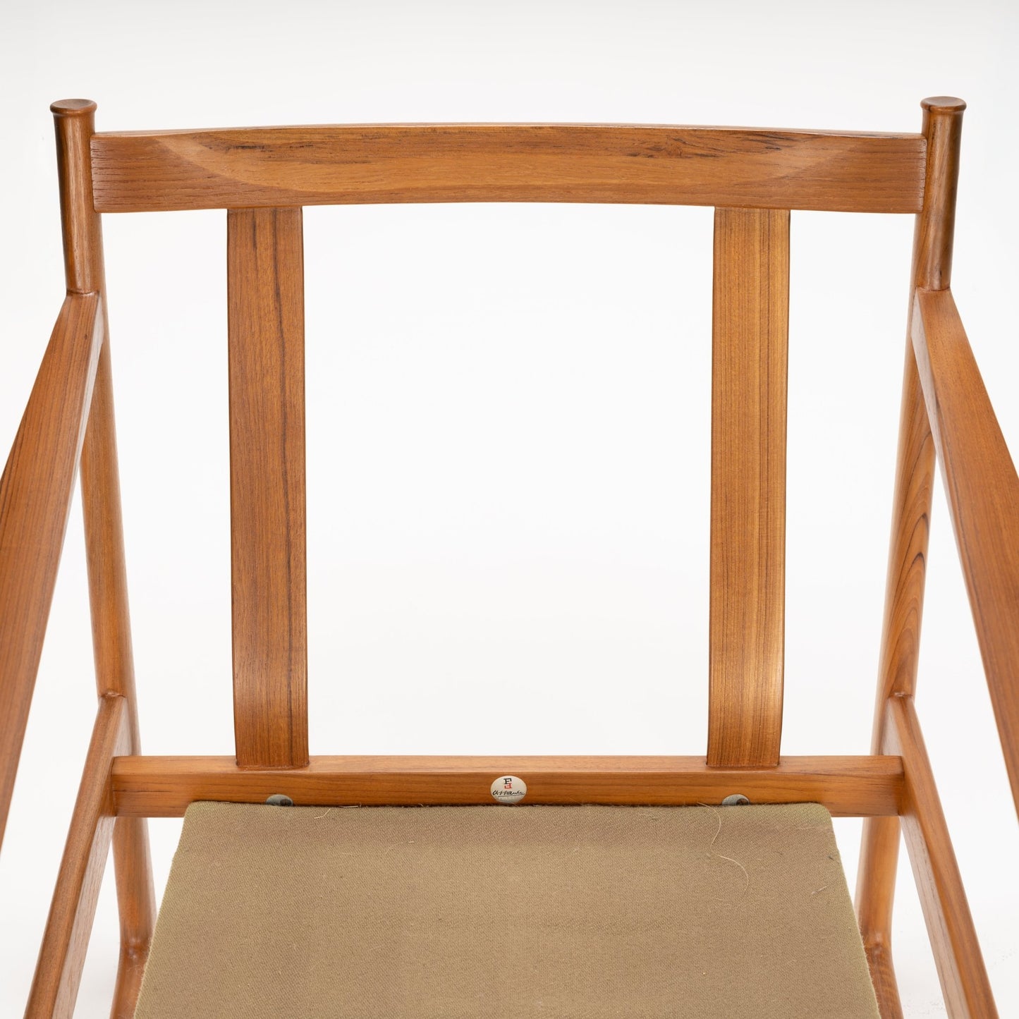 Top-down view of a wooden chair frame with vertical slats and a light brown fabric seat on white background