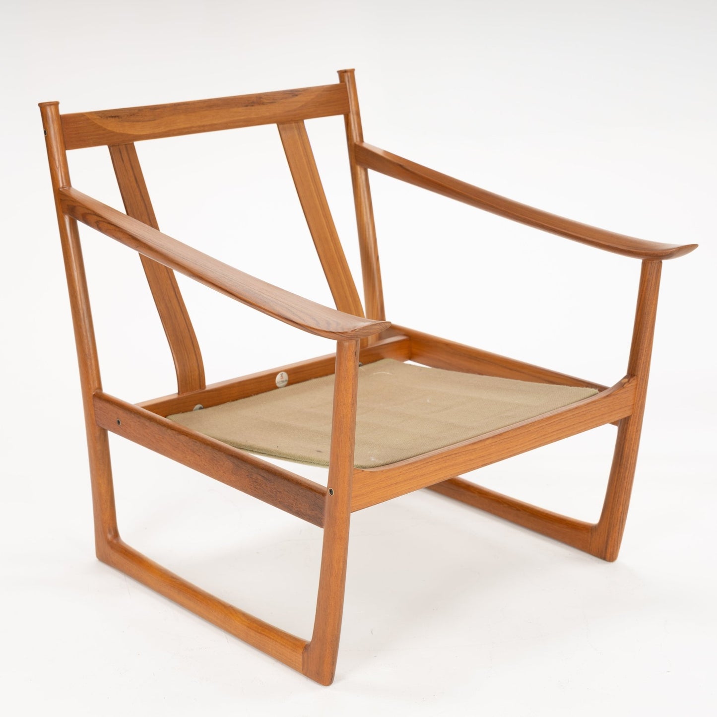 Open-frame wooden chair with wide carved armrests and tan fabric seat sling on a white background