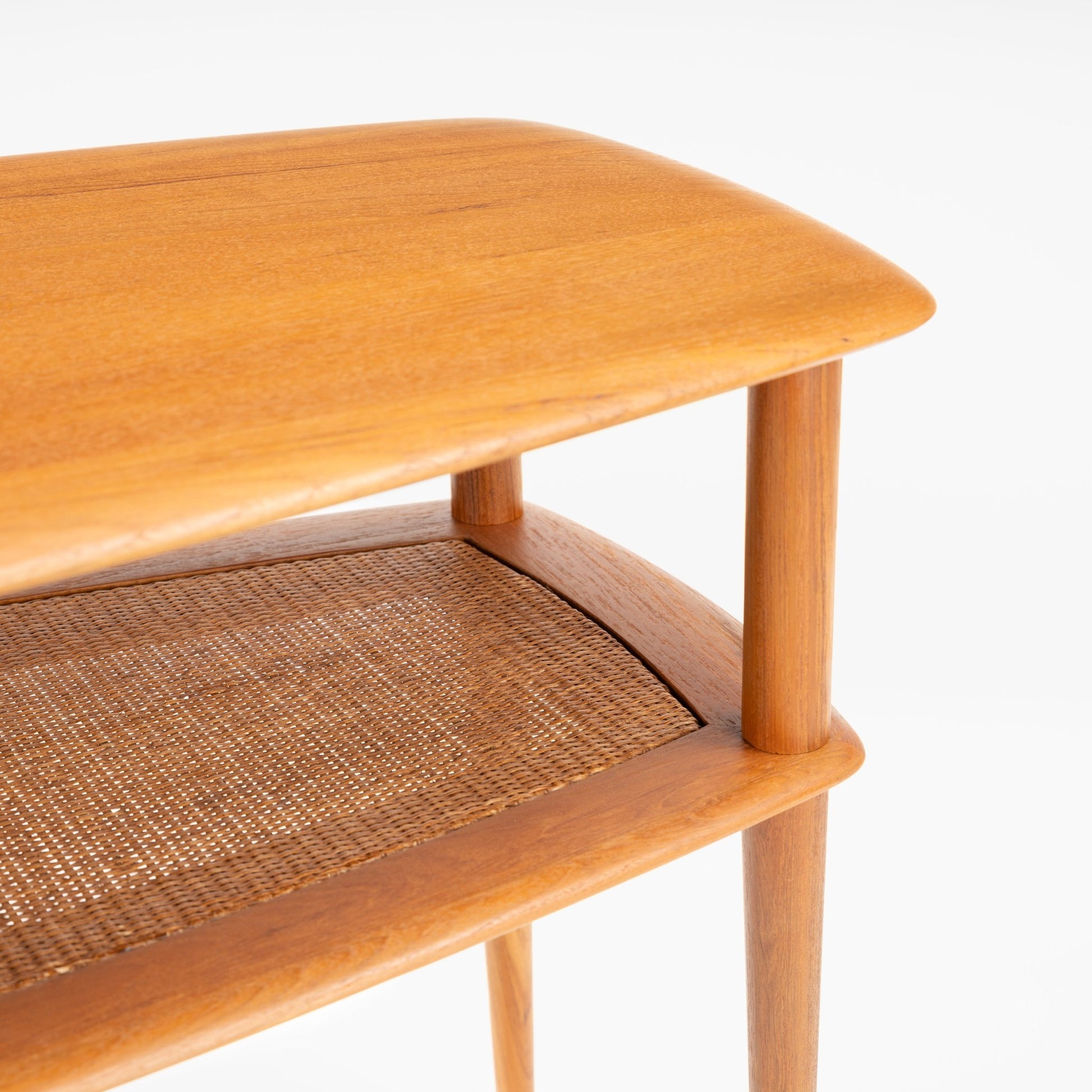 Peter Hvidt & Orla Molgaard Pair of End Tables featuring a smooth, rounded wooden top with warm tones, a finely woven cane shelf below, and slender tapered legs in mid century modern style.