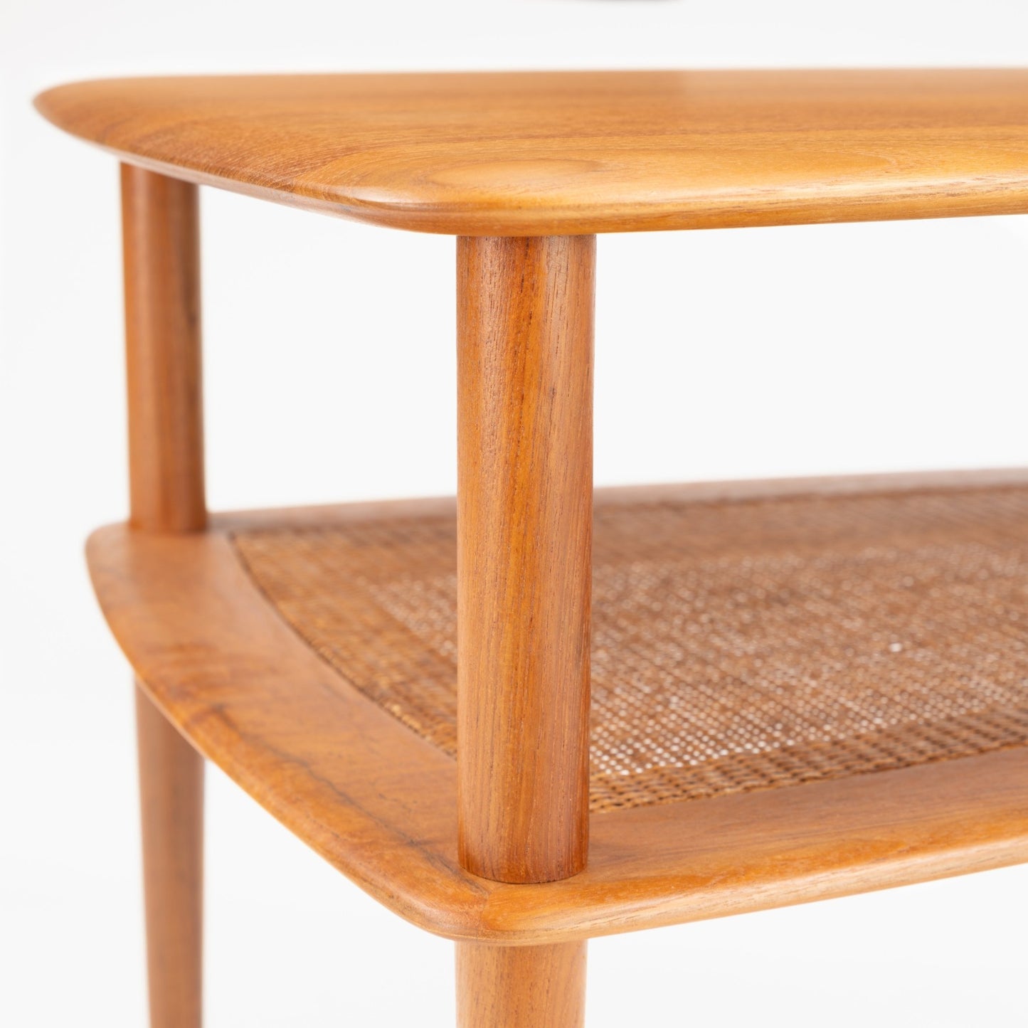 Peter Hvidt & Orla Molgaard Pair of End Tables with finely rounded wooden edges, smooth cylindrical legs, and a woven cane shelf highlighting vintage Danish mid century modern design.
