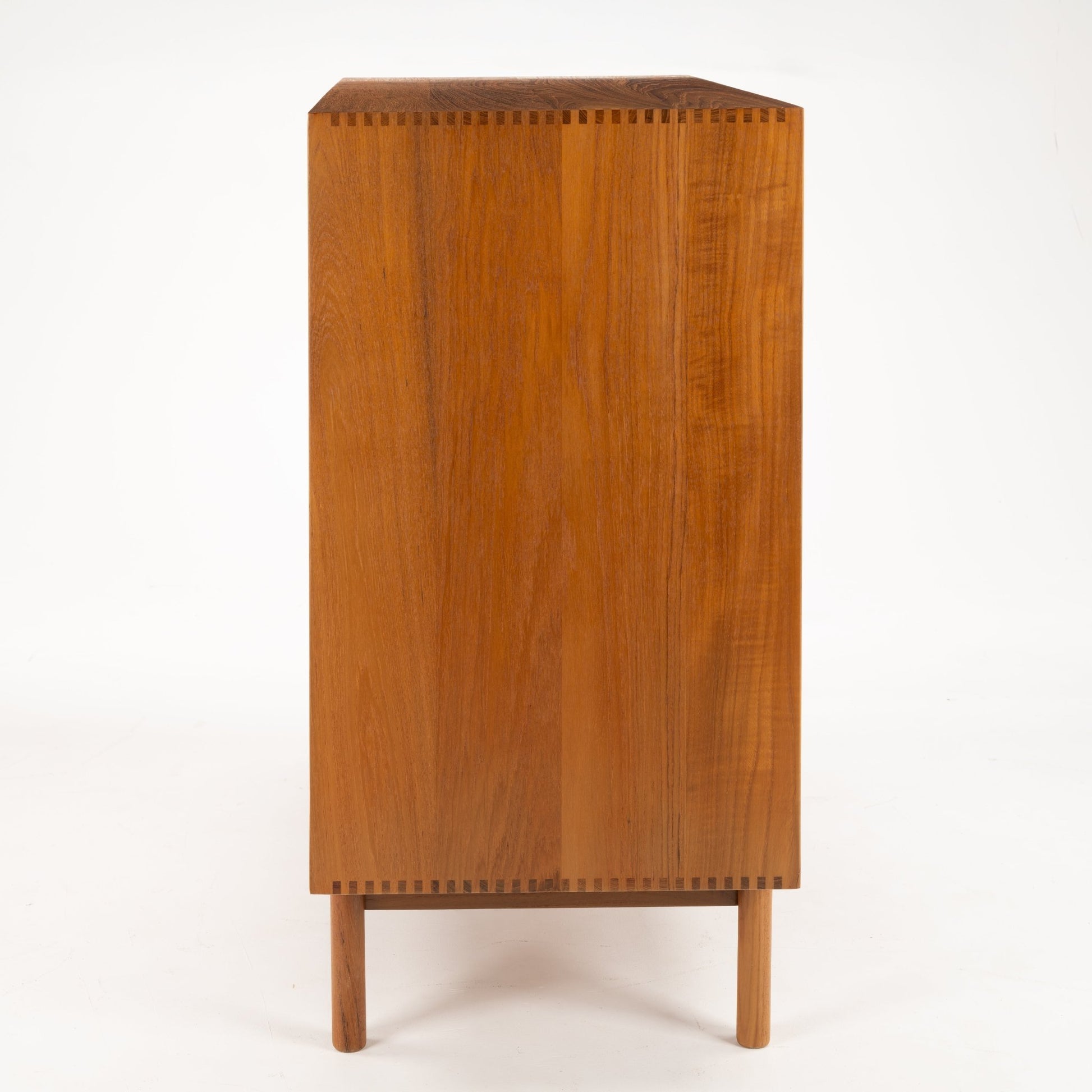 Peter Hvidt & Orla Nielsen Teak Chest of Drawers showing the side view with rich teak wood grain, precise dovetail joinery, and slender round legs in vintage Danish mid century modern style.