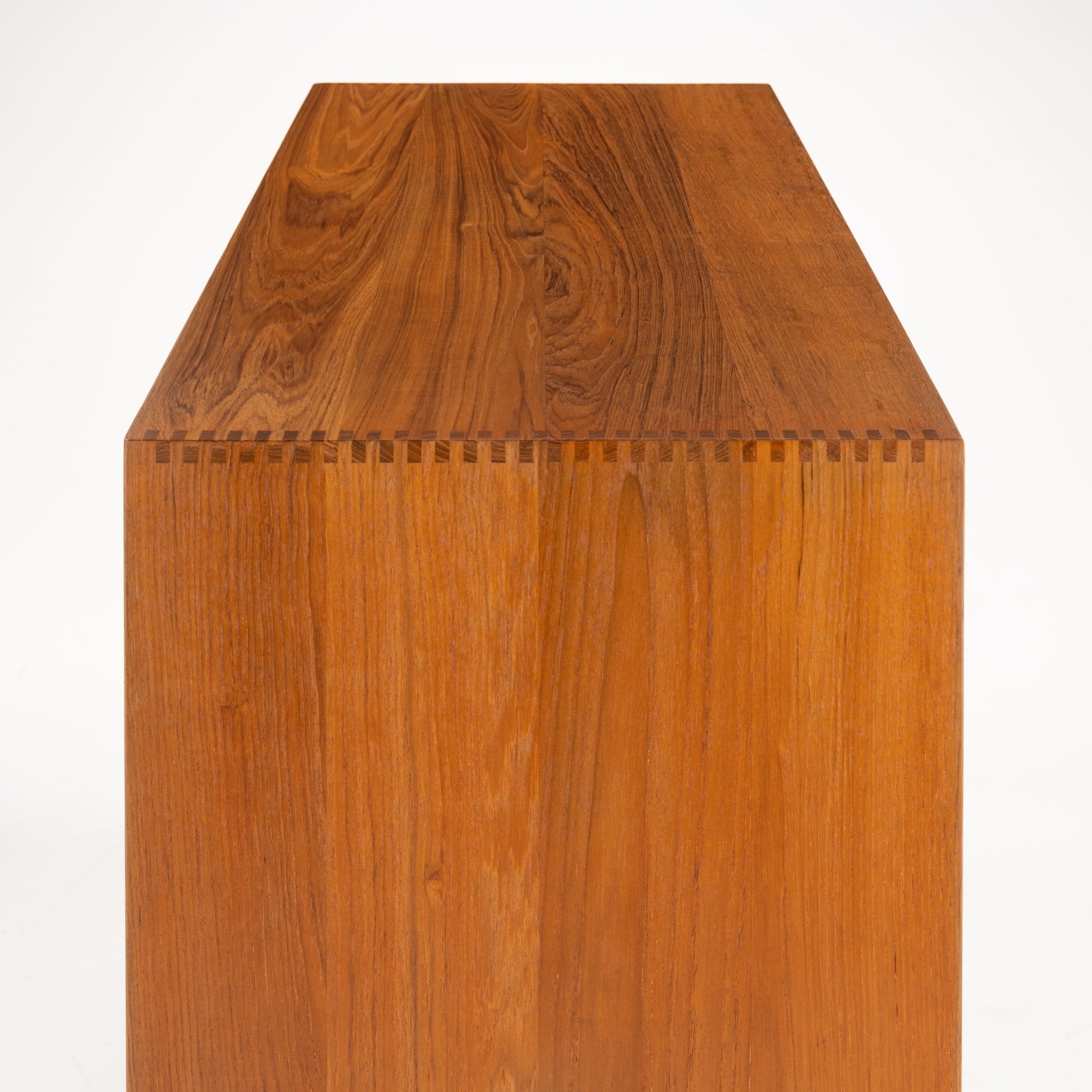 Peter Hvidt & Orla Nielsen Teak Chest of Drawers showing a close-up of finely crafted dovetail joinery joining the smooth teak wood top and side panels with rich grain detail in vintage mid century modern style.