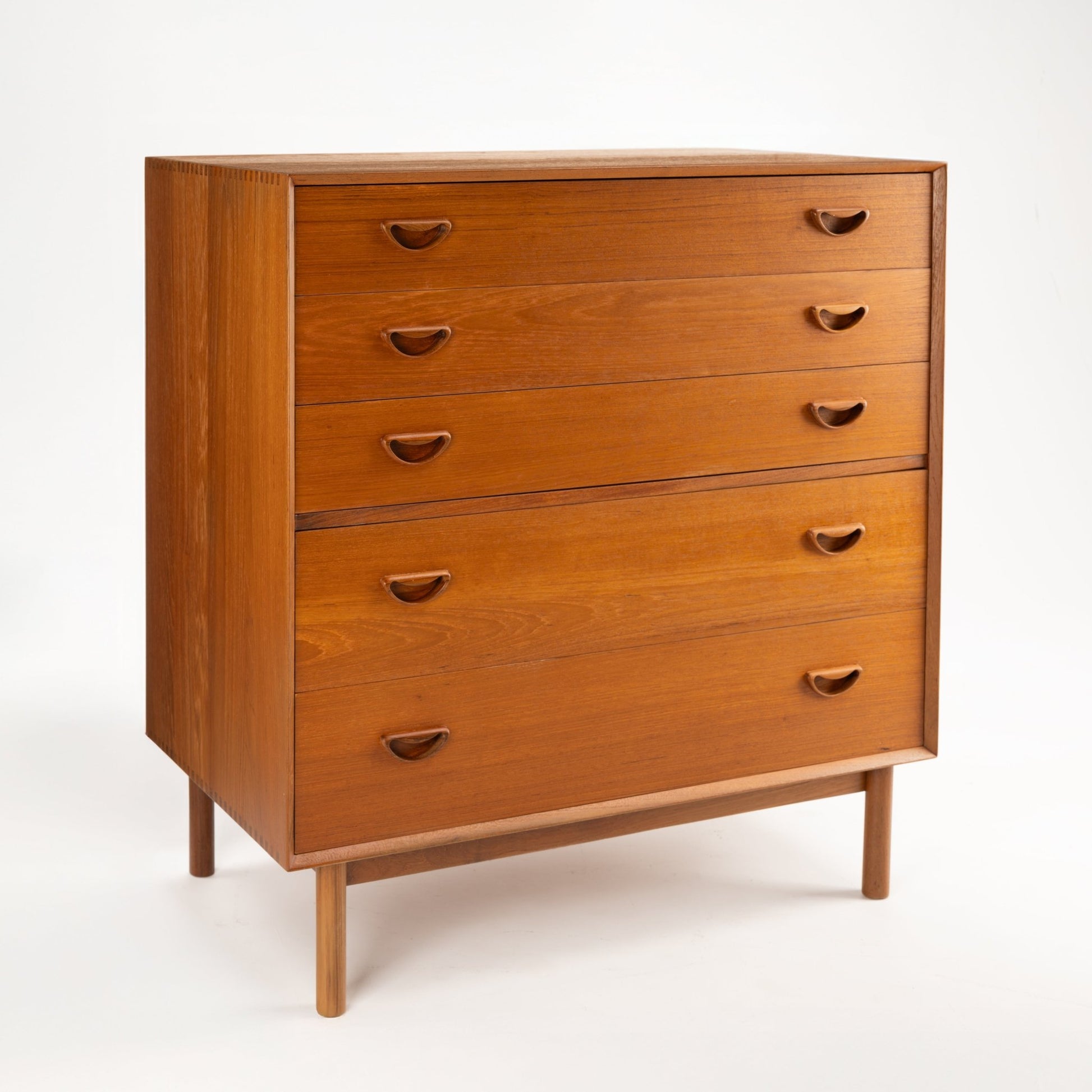 Peter Hvidt & Orla Nielsen Teak Chest of Drawers featuring warm teak wood with four drawers and distinctive curved recessed handles, standing on slender round legs in vintage Danish mid century modern style.