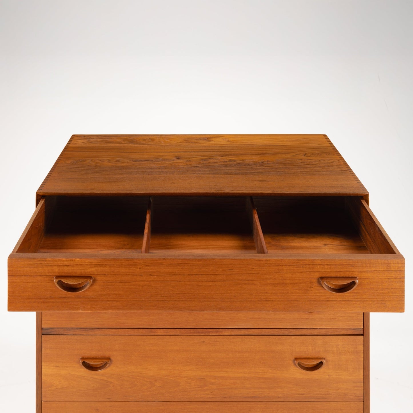 Peter Hvidt & Orla Nielsen Teak Chest of Drawers featuring warm teak wood with an open top drawer divided into three compartments and distinctive curved recessed handles in vintage mid century modern style.