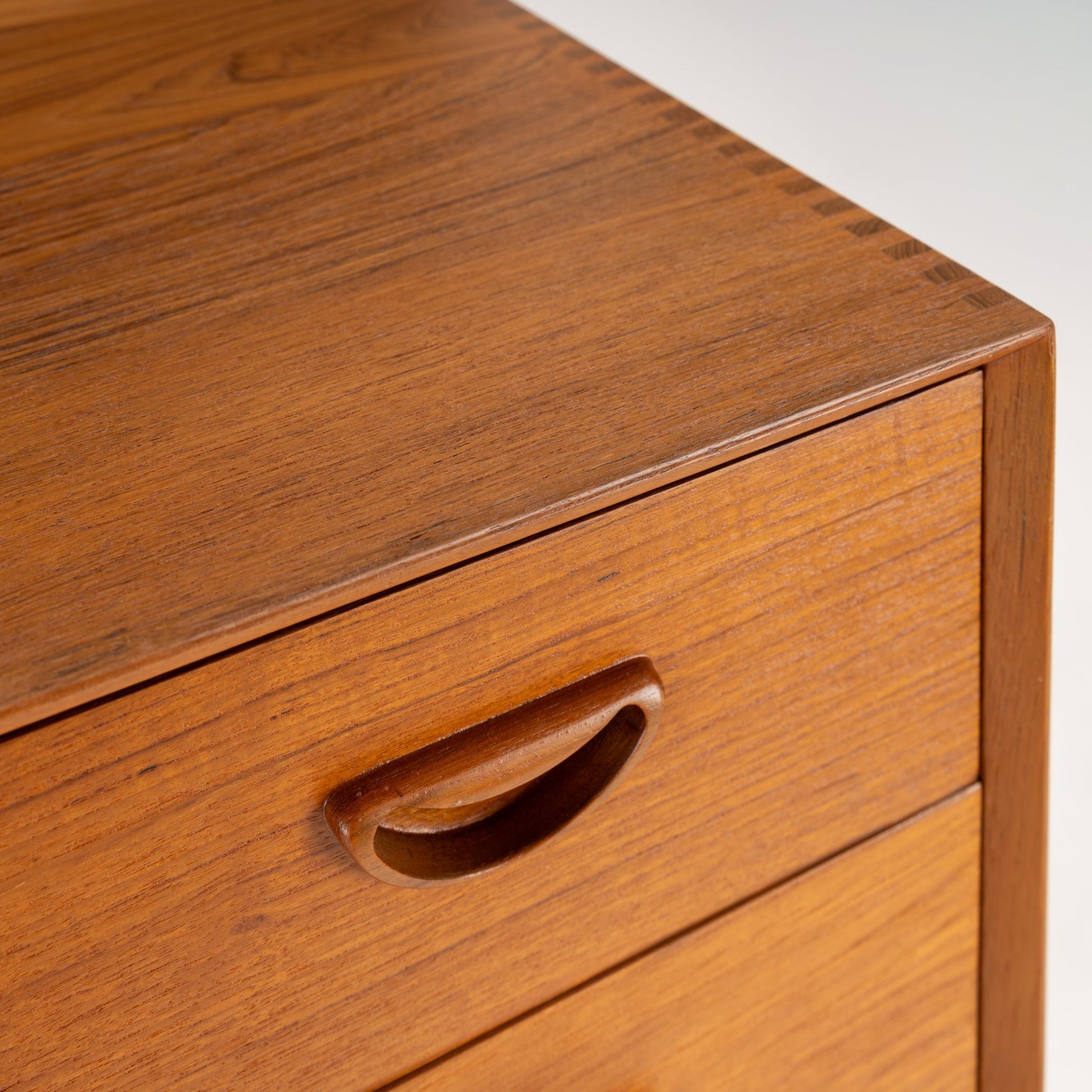 Peter Hvidt & Orla Nielsen Teak Chest of Drawers showcasing smooth teak wood with a close-up of a single drawer featuring a carved recessed handle and fine grain detail in vintage Danish mid century modern style.