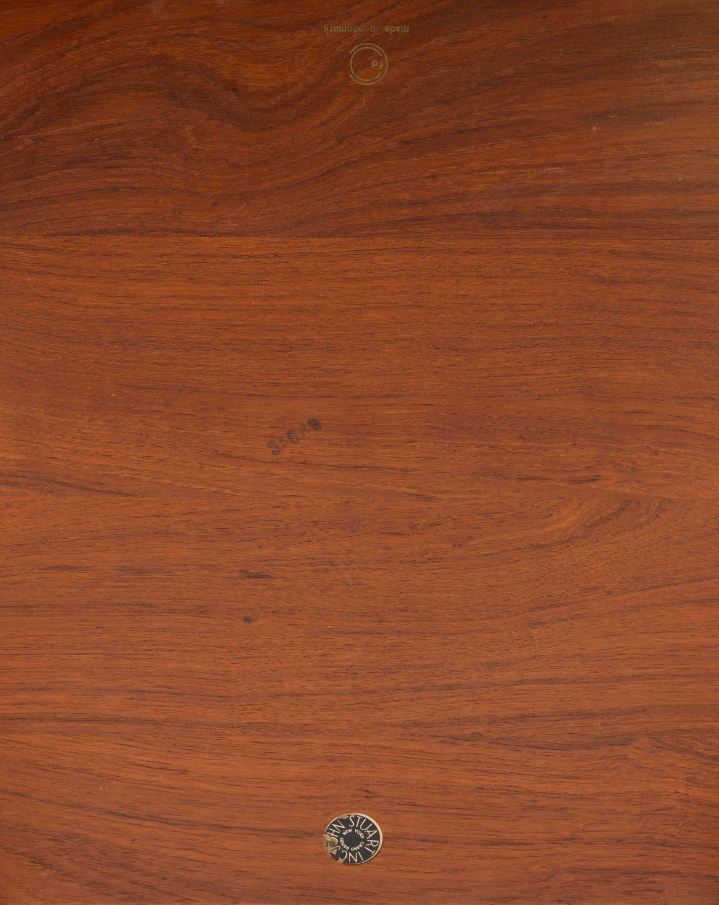 Close-up of solid teak wood tabletop from Peter Hvidt side table showing natural grain and John Stuart Inc label.
