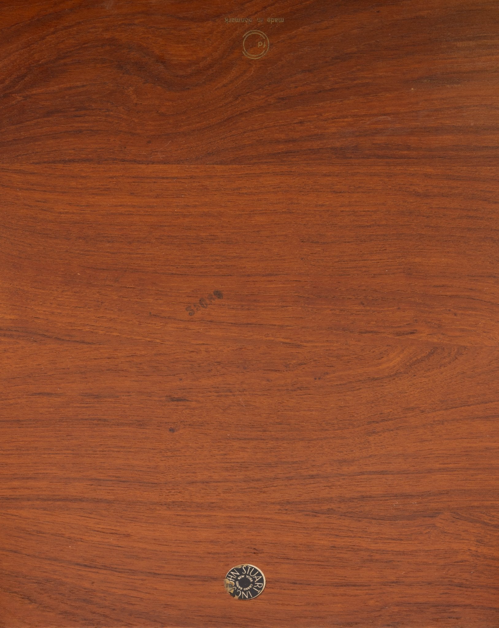 Close-up of solid teak wood tabletop from Peter Hvidt side table showing natural grain and John Stuart Inc label.