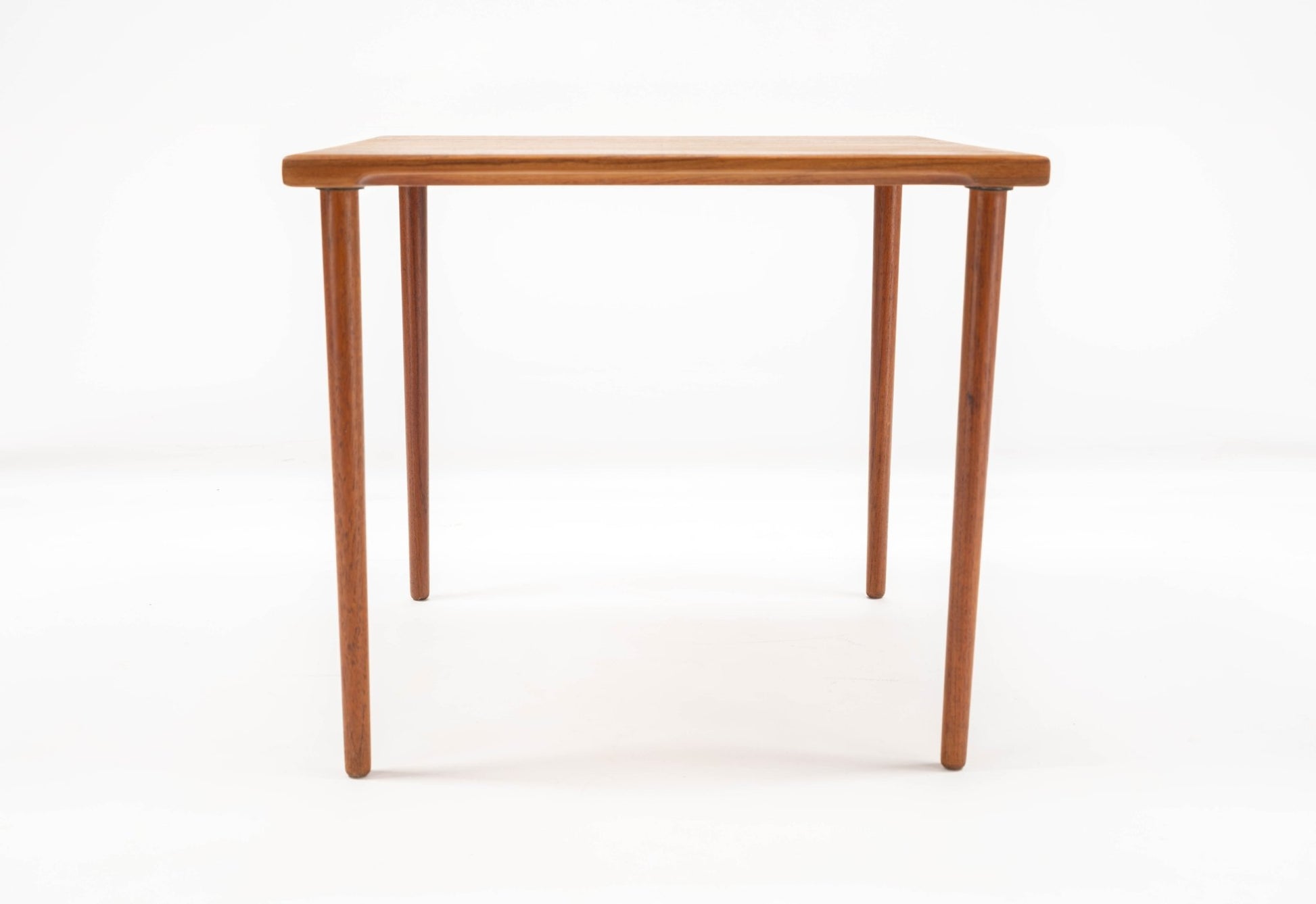 1960s Danish teak side table by Peter Hvidt with slender dowel legs and solid teak slab top on white background