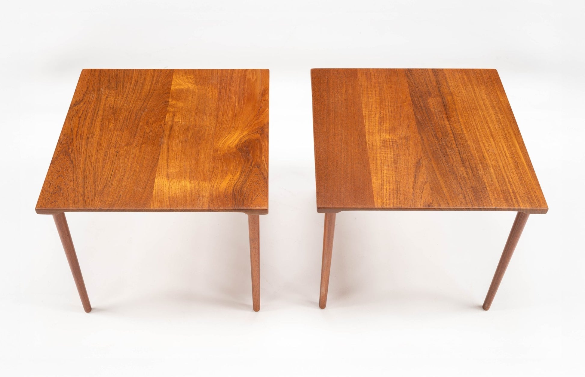 Pair of mid-century modern Danish teak side tables with rectangular tops and slender dowel legs on white background