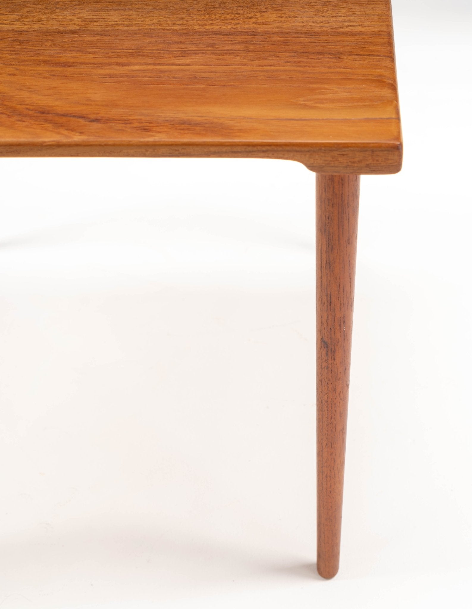 Close-up of mid-century modern Peter Hvidt teak side table leg and finely grained tabletop with tapered dowel detail.