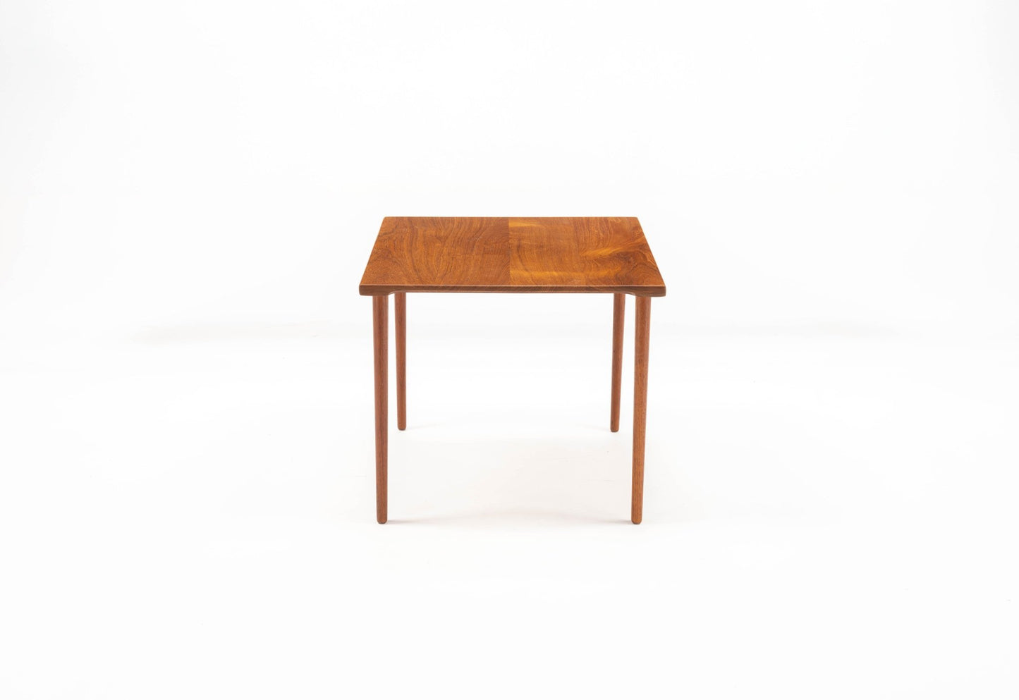 Mid-century modern Peter Hvidt teak side table with slender dowel legs and single slab wood top on white background