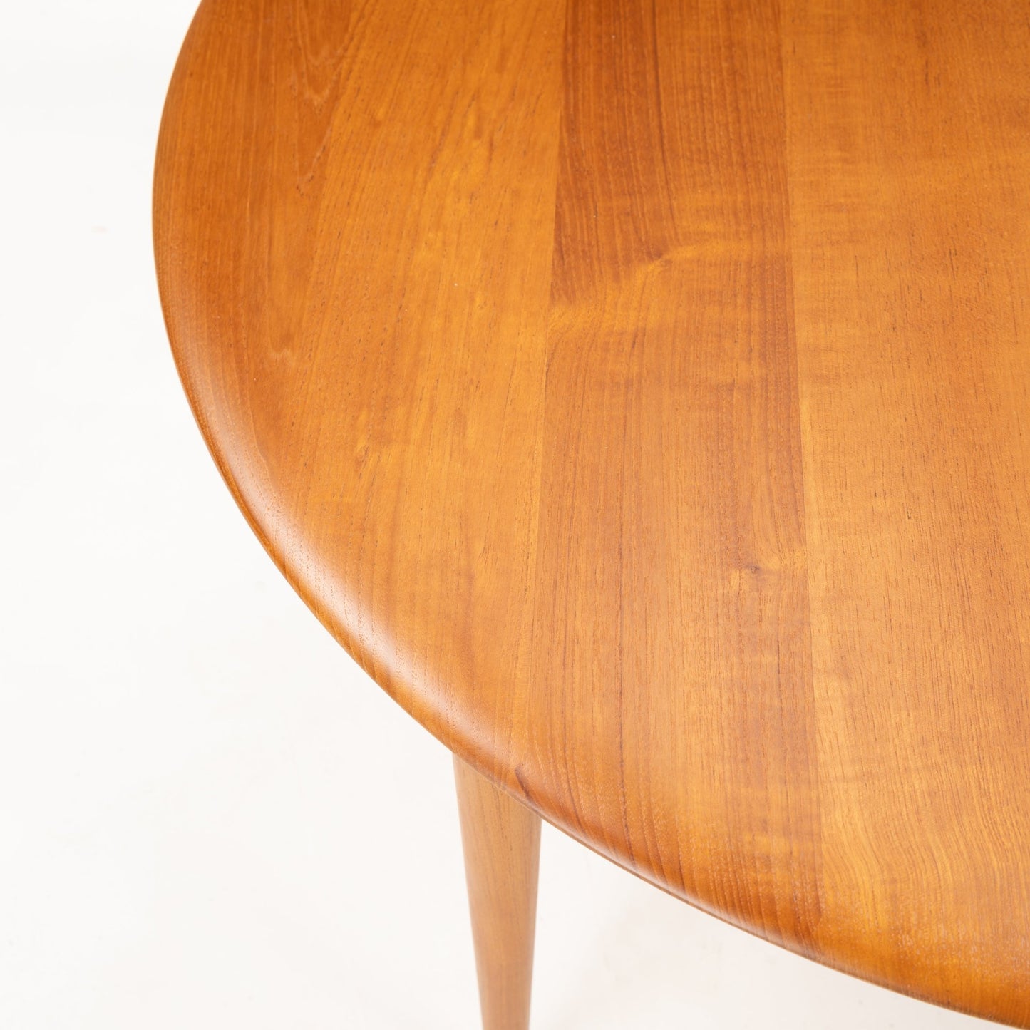 Peter Hvidt Teak Coffee Table Model FD-515 with a close-up of its smooth round teak top and tapered leg tip, highlighting the warm wood grain and craftsmanship of vintage mid century modern furniture.
