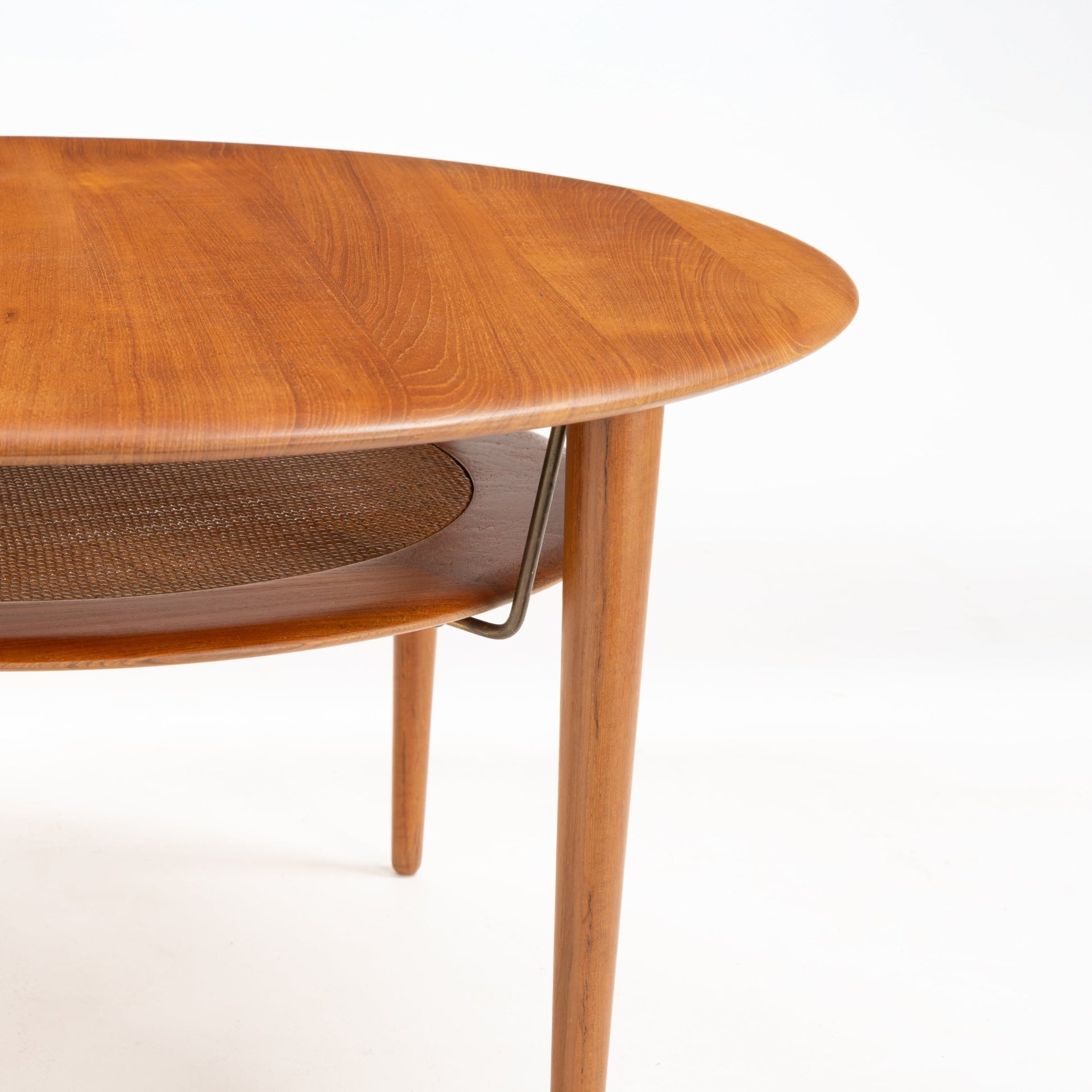 Peter Hvidt Teak Coffee Table Model FD-515 showing a gently rounded teak top with visible grain and tapered legs supporting a lower woven shelf, reflecting mid century modern furniture design.