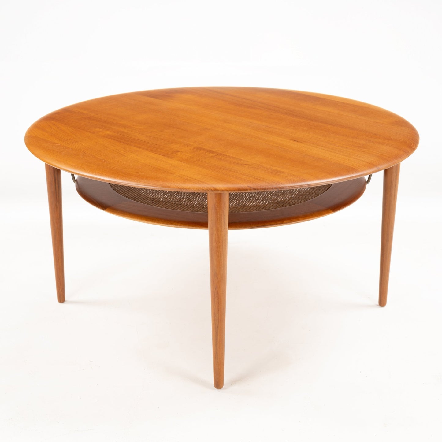 Peter Hvidt Teak Coffee Table Model FD-515 with a smooth round teak top, slender tapered legs, and a woven circular shelf below, showcasing elegant mid century modern design.