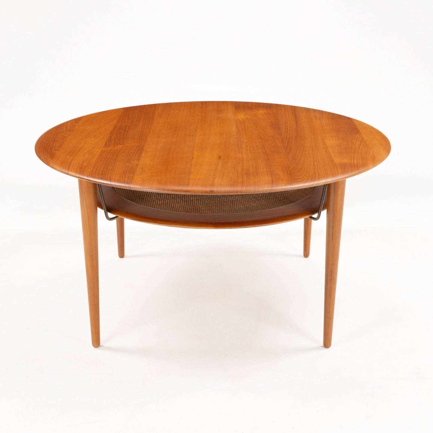 Peter Hvidt Teak Coffee Table Model FD-515 showcasing a round teak wood surface with a smooth finish and slender tapered legs, featuring a lower woven shelf in mid century modern style.