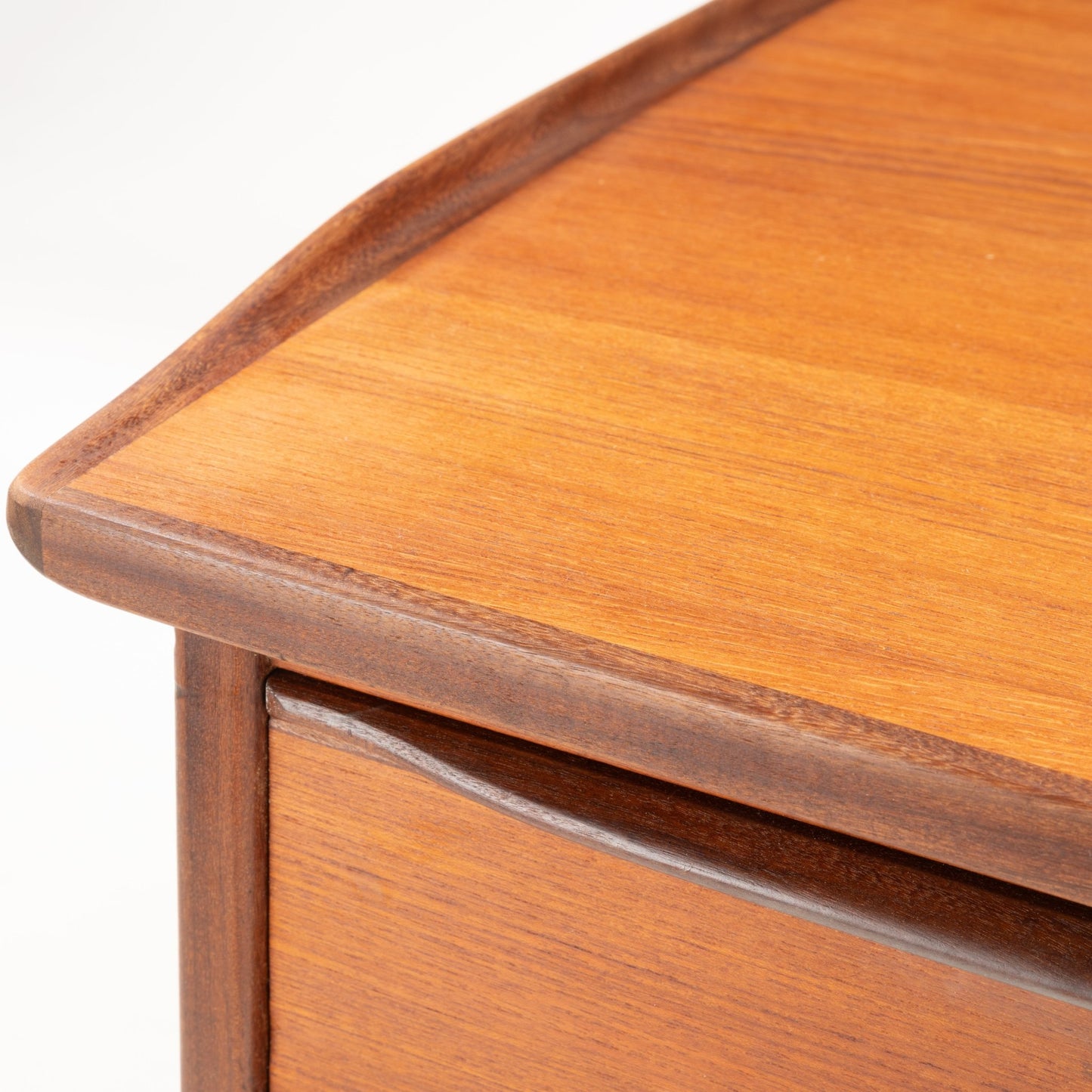 Close-up of 1960s Danish teak desk corner showing curved edge and smooth wood grain craftsmanship
