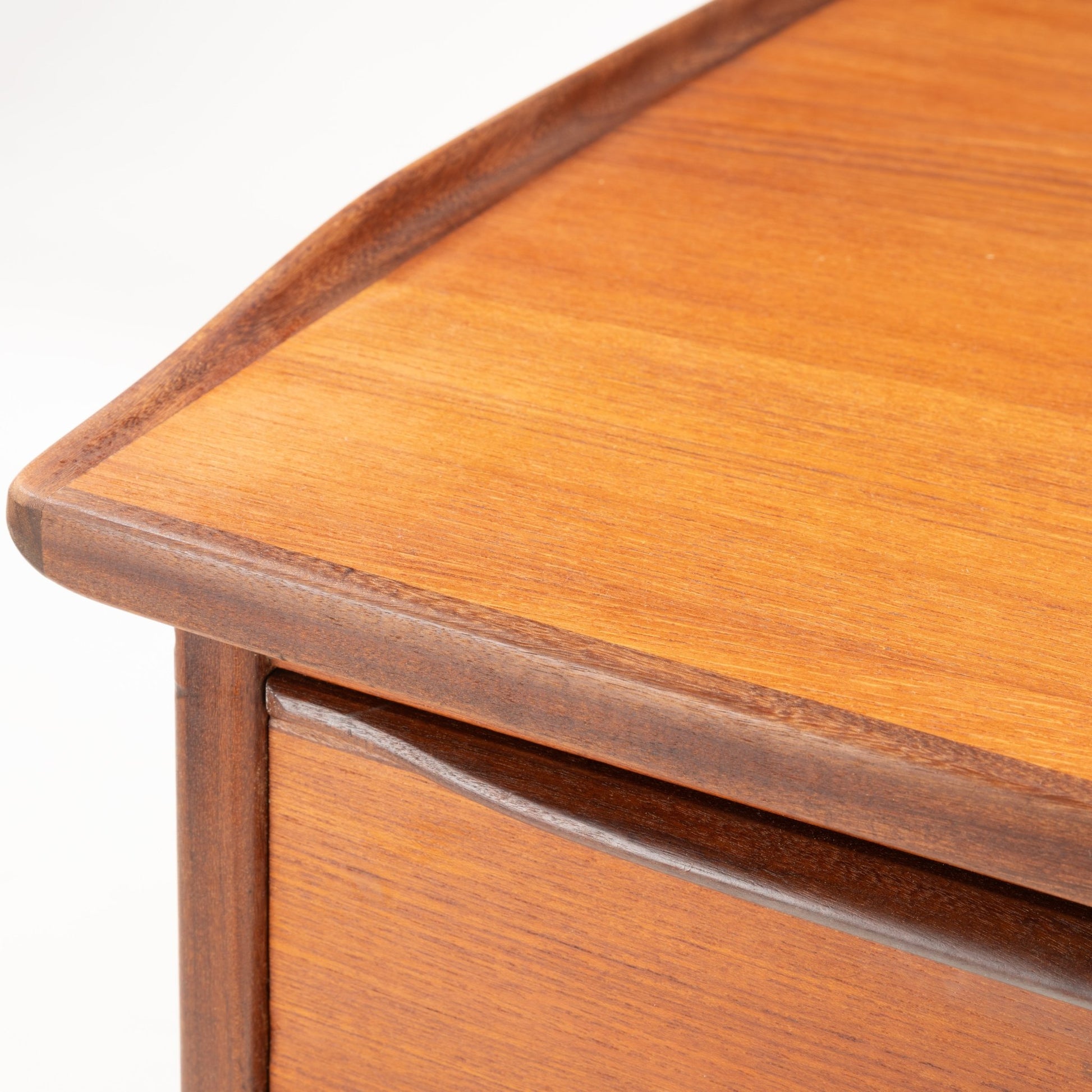 Close-up of 1960s Danish teak desk corner showing curved edge and smooth wood grain craftsmanship