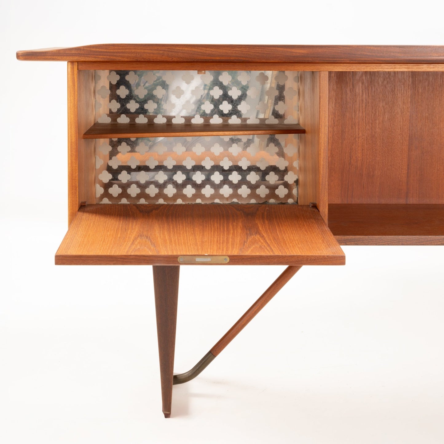 Open storage compartment of 1960s Danish teak desk with patterned interior and angled tapered leg detail