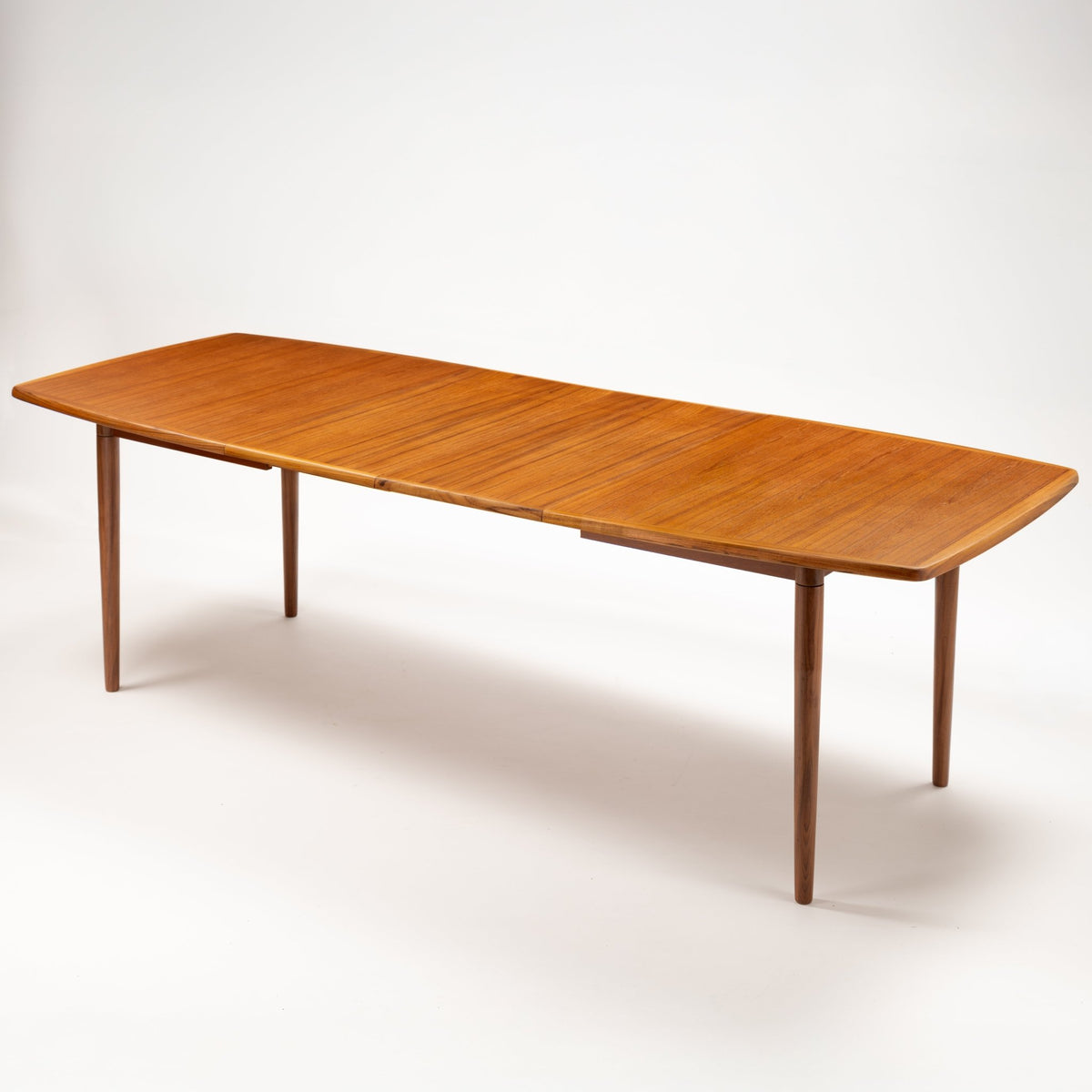 Rastad & Relling Extension Dining Table in warm teak with an extended rounded rectangular top and tapered legs in mid century modern furniture style