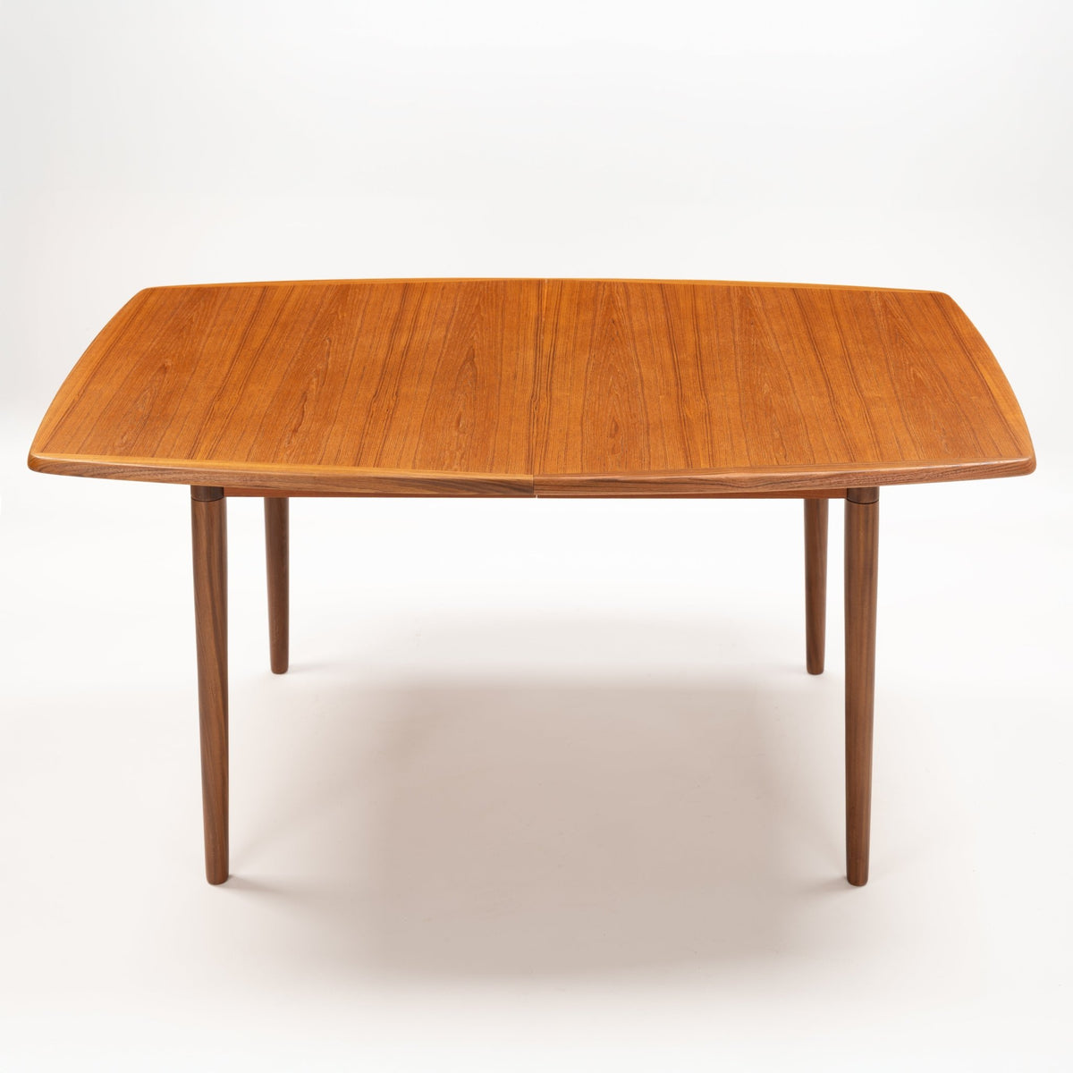 Rastad & Relling Extension Dining Table in warm teak with a rounded rectangular top and slender tapered legs in mid century modern furniture style