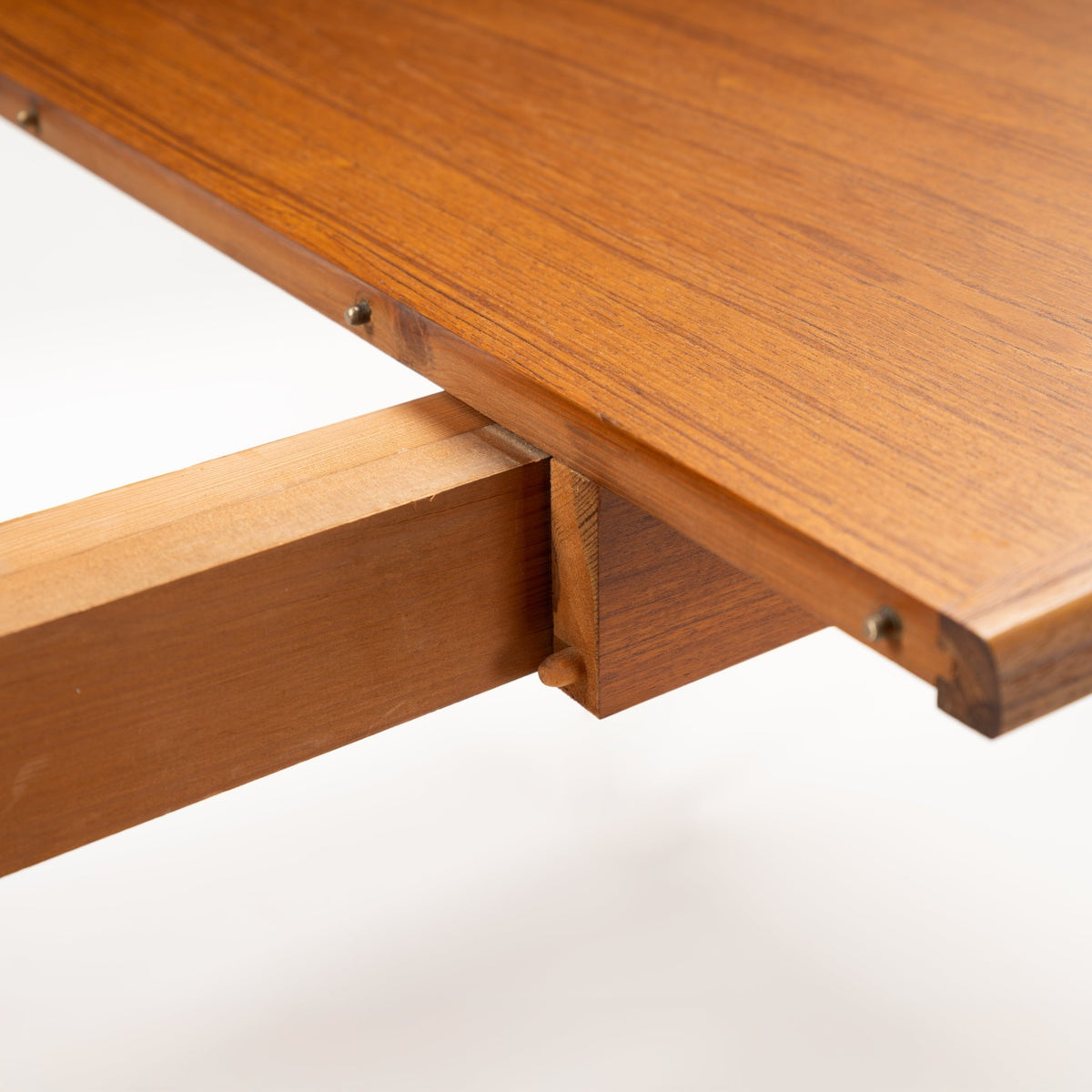Rastad & Relling Extension Dining Table close-up showing the teak extension rail and support mechanism beneath its rounded top in mid century modern furniture style