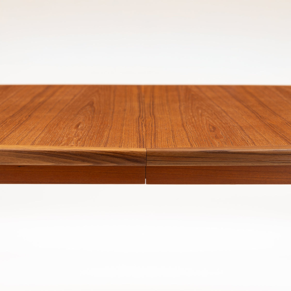 Rastad & Relling Extension Dining Table close-up showing rich teak grain and a precise center seam across its joined tabletop in mid century modern furniture style
