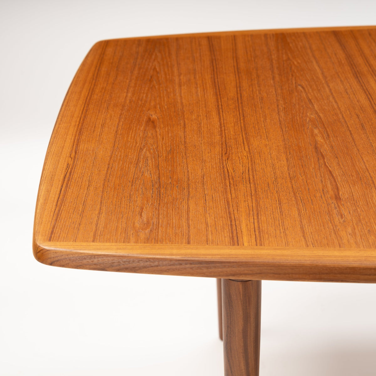 Rastad & Relling Extension Dining Table close-up highlighting the rounded teak tabletop corner and tapered wooden leg in mid century modern furniture style