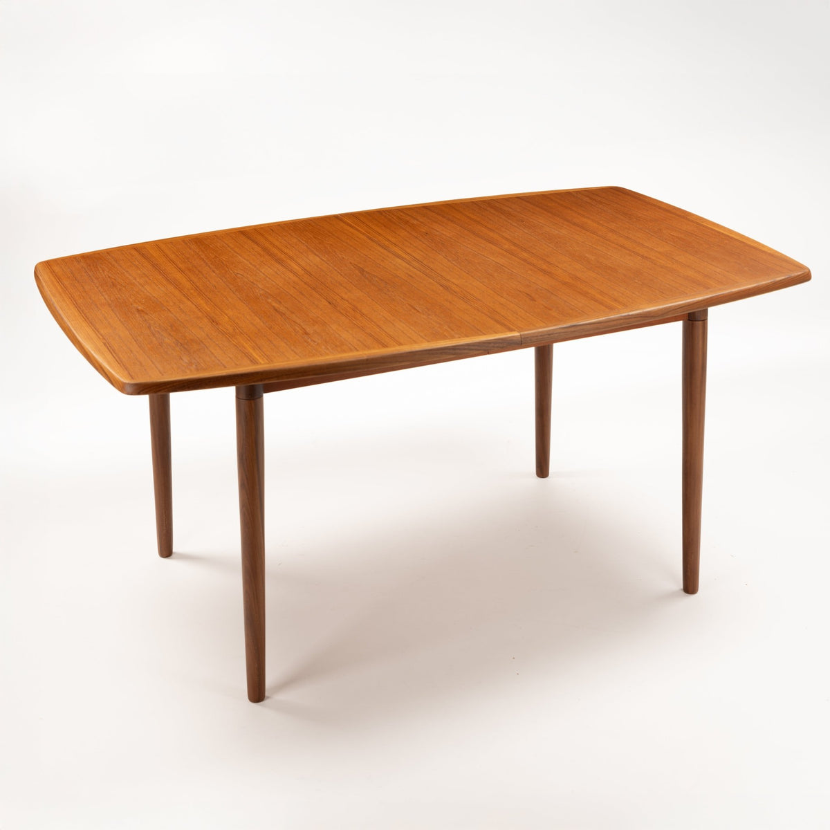 Rastad & Relling Extension Dining Table in warm teak with rounded rectangular top and tapered legs shown closed in mid century modern furniture style