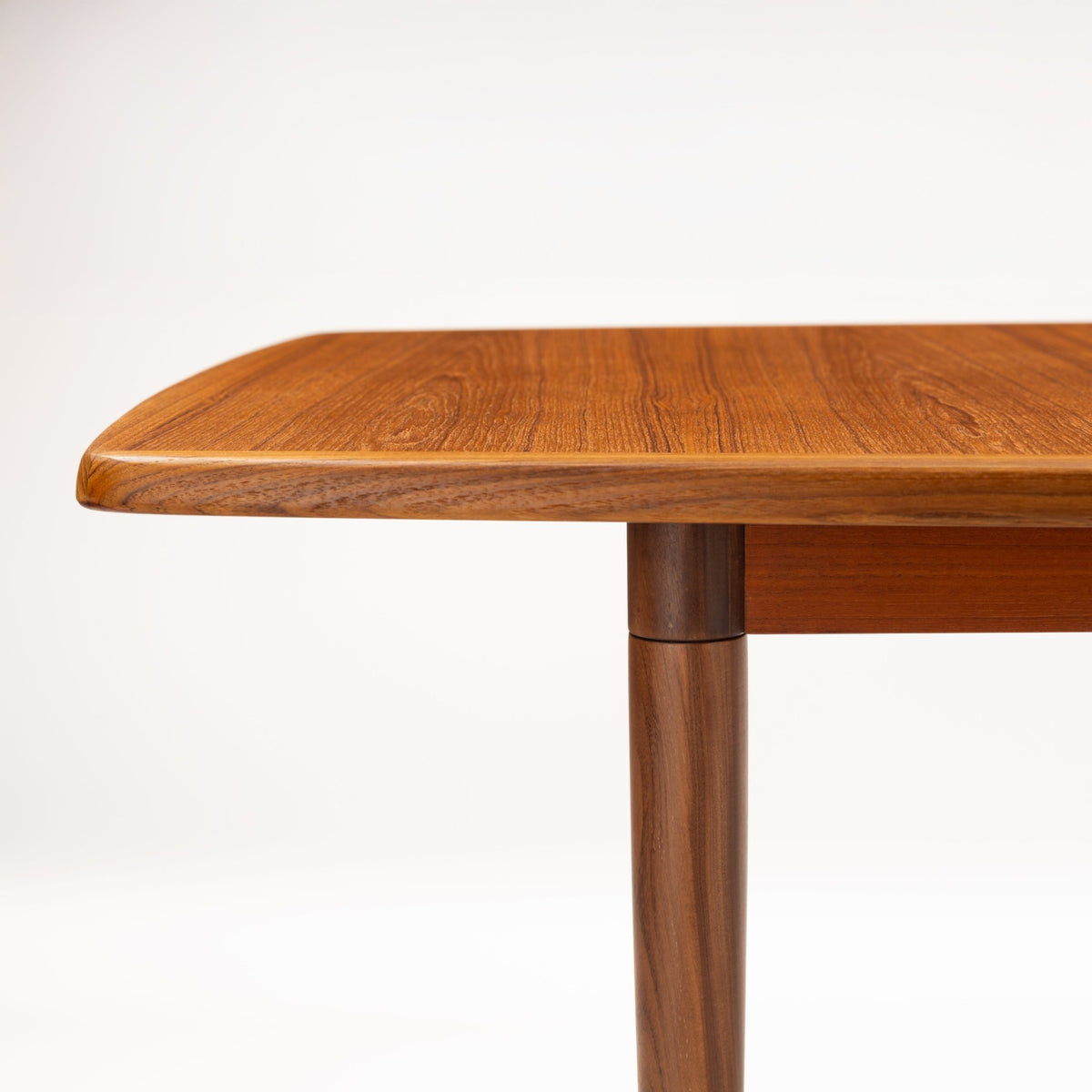 Rastad & Relling Extension Dining Table close detail of warm teak rounded tabletop edge and sculpted leg in mid century modern furniture style