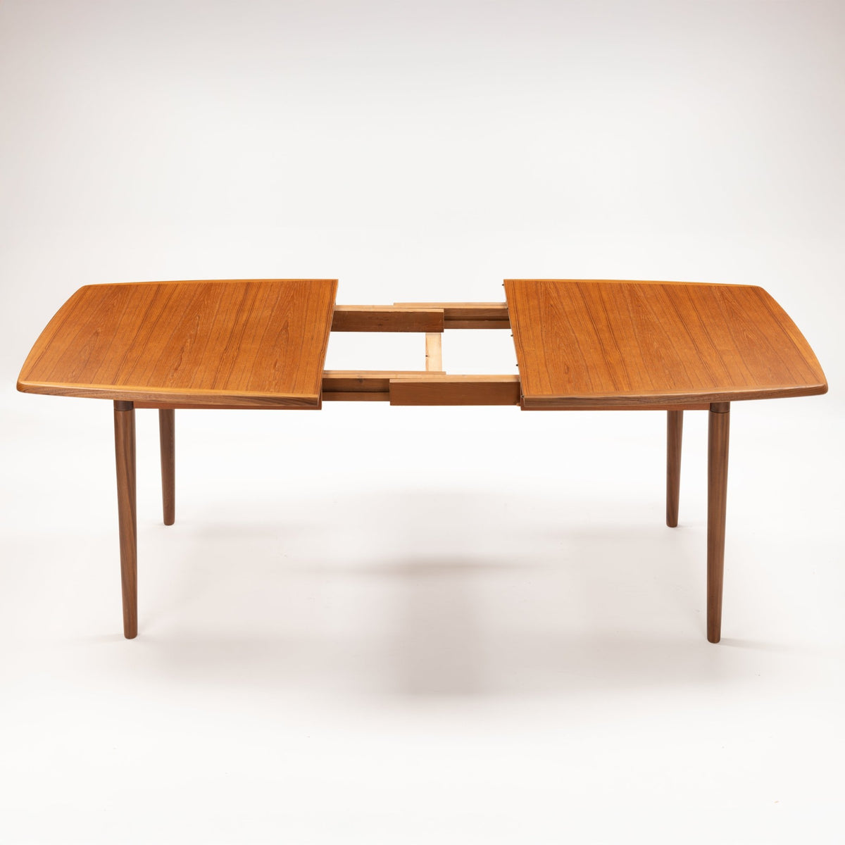 Rastad & Relling Extension Dining Table in warm teak shown extended with two leaves and slender tapered legs in mid century modern furniture style