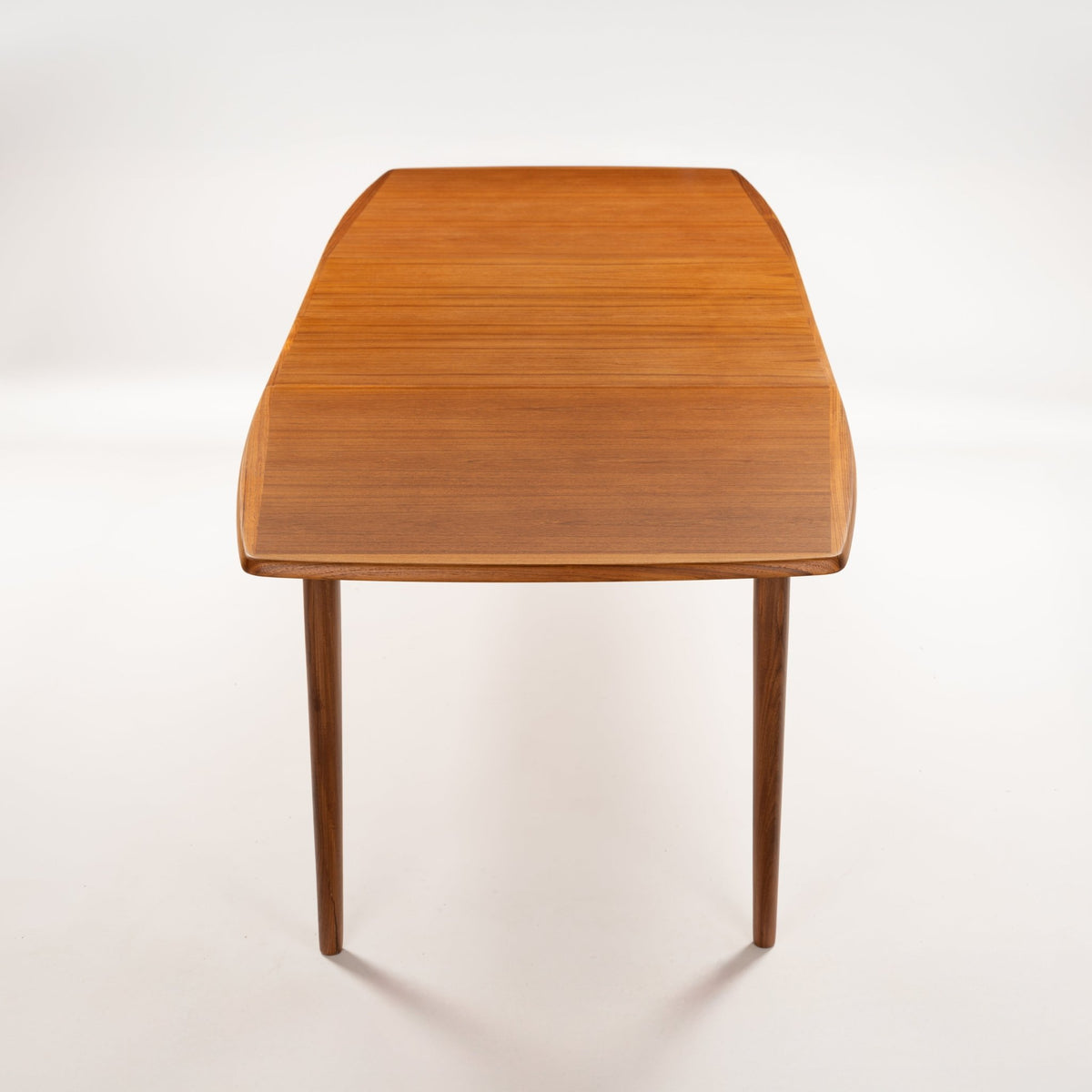 Rastad & Relling Extension Dining Table in warm teak with a rounded top and slender tapered legs in mid century modern furniture style