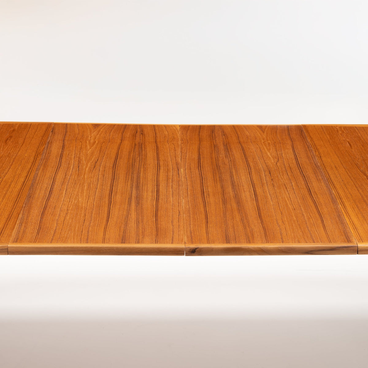 Rastad & Relling Extension Dining Table close view of rich teak grain across its extended top highlighting the central leaf joint in mid century modern furniture style