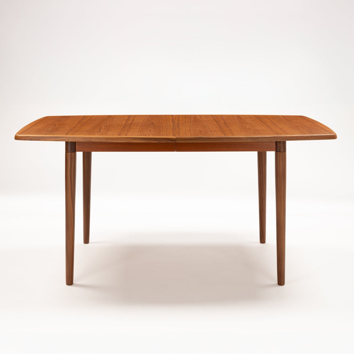 Rastad & Relling Extension Dining Table in warm teak with a rounded rectangular top and four slender tapered legs in mid century modern furniture style