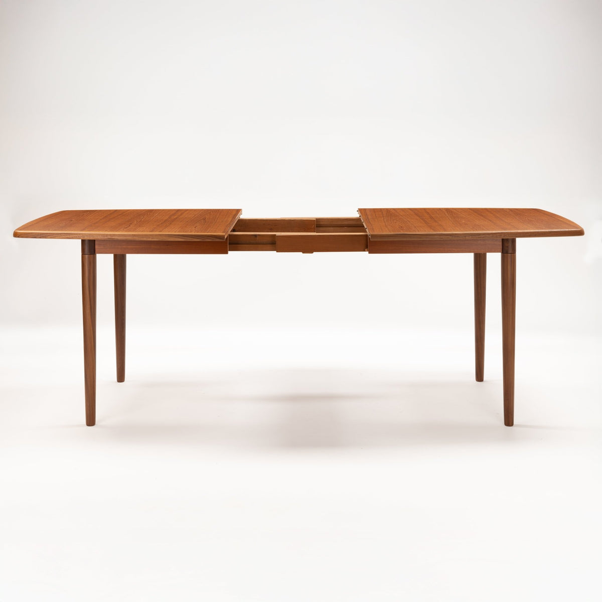 Rastad & Relling Extension Dining Table shown extended in warm teak with separated tabletop leaves and visible extension mechanism on tapered legs in mid century modern furniture style
