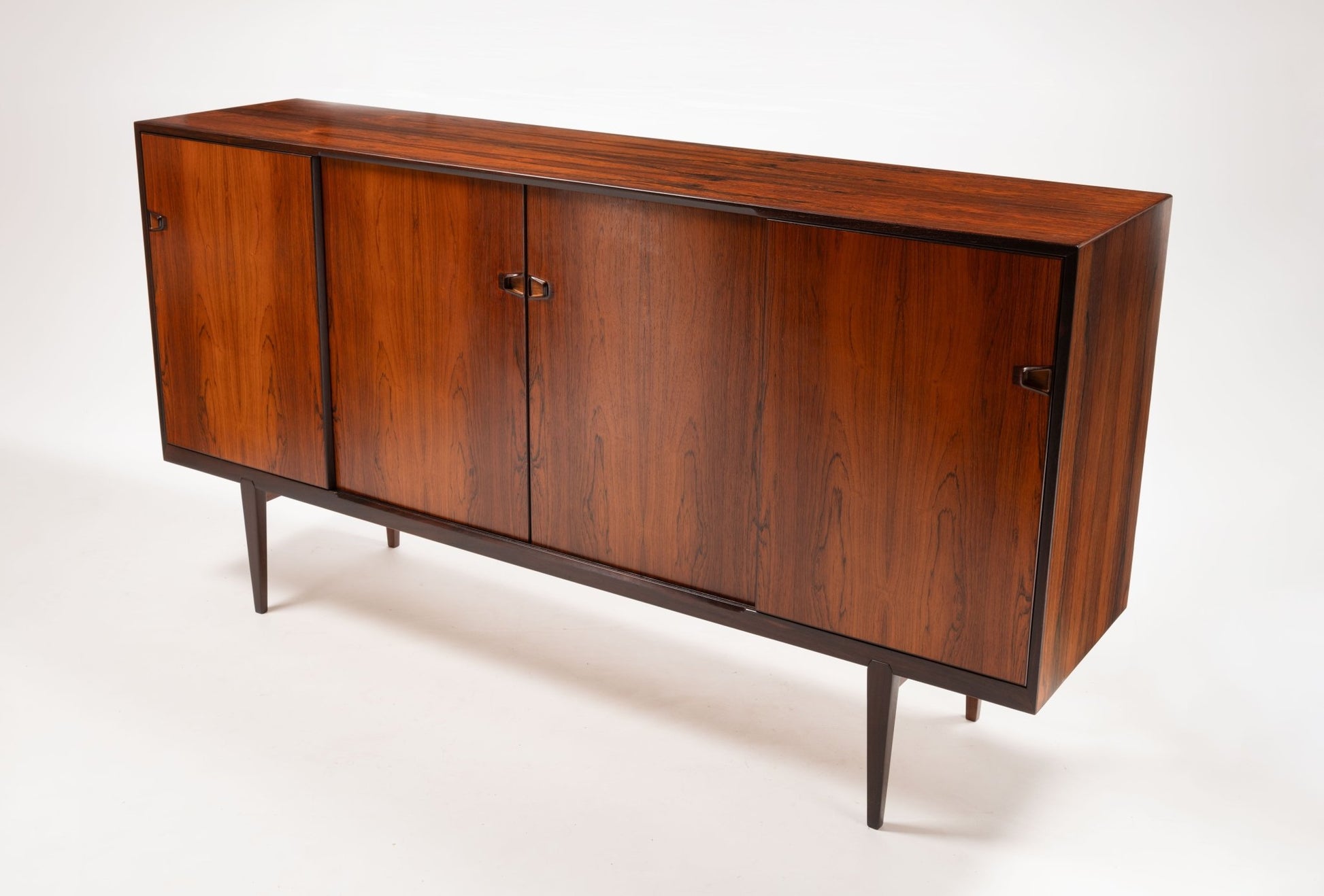 Mid-century modern rosewood credenza with sculpted handles and tapered legs designed by Henry Rosengren Hansen.