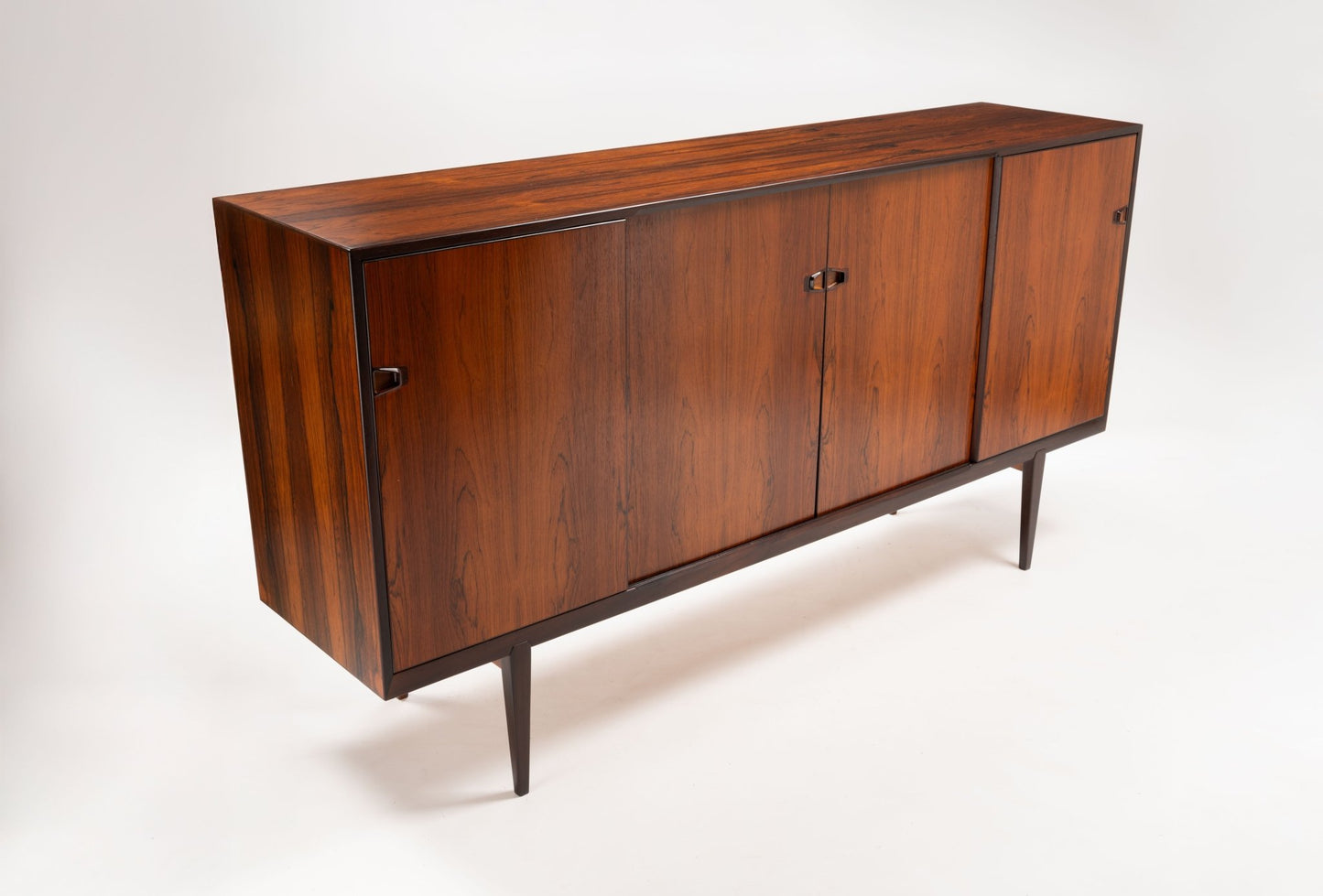 Mid-century modern rosewood credenza with sculpted handles and tapered legs, designed by Henry Rosengren Hansen.